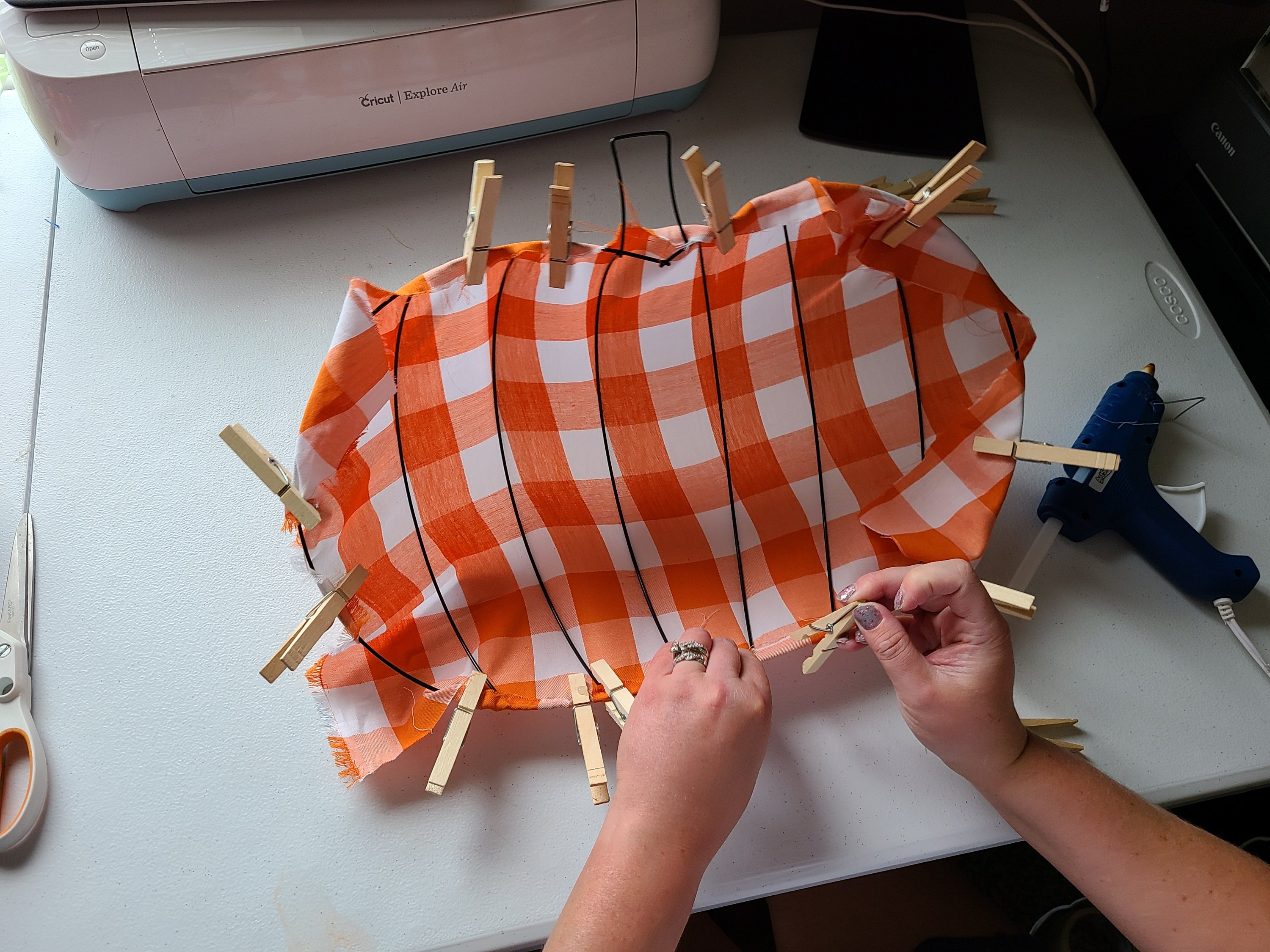Using clothes pins to attach fabric to the Dollar Tree pumpkin wreath form.