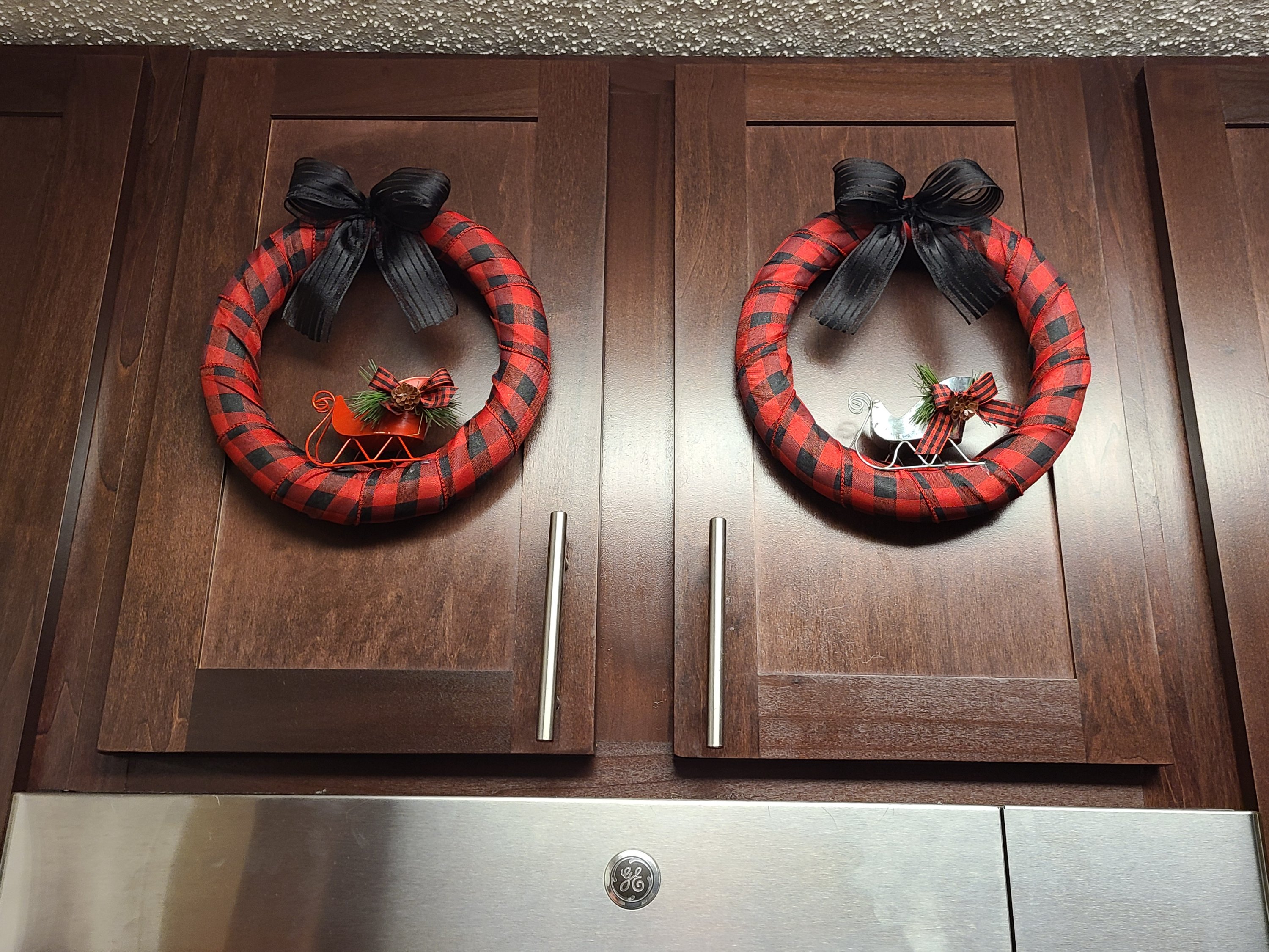 Two Christmas buffalo check wreaths on cabinet doors.
