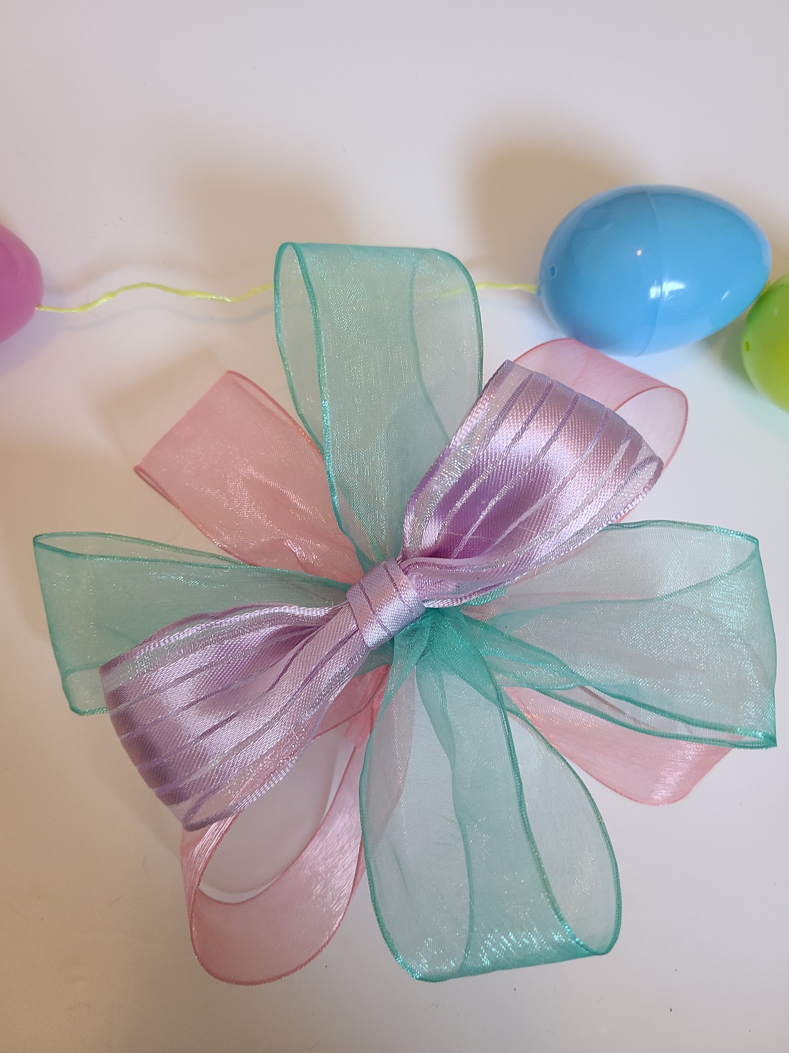 Bow with ten loops made up of 1.5" lavender, pink, and aqua ribbon.