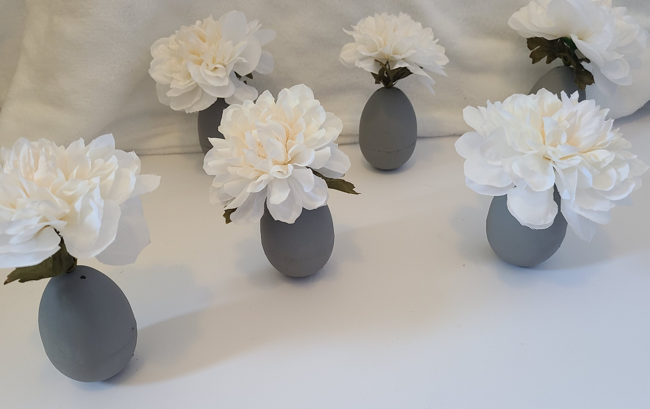 Set of 6 Easter egg vases with white flowers and gray painted eggs.
