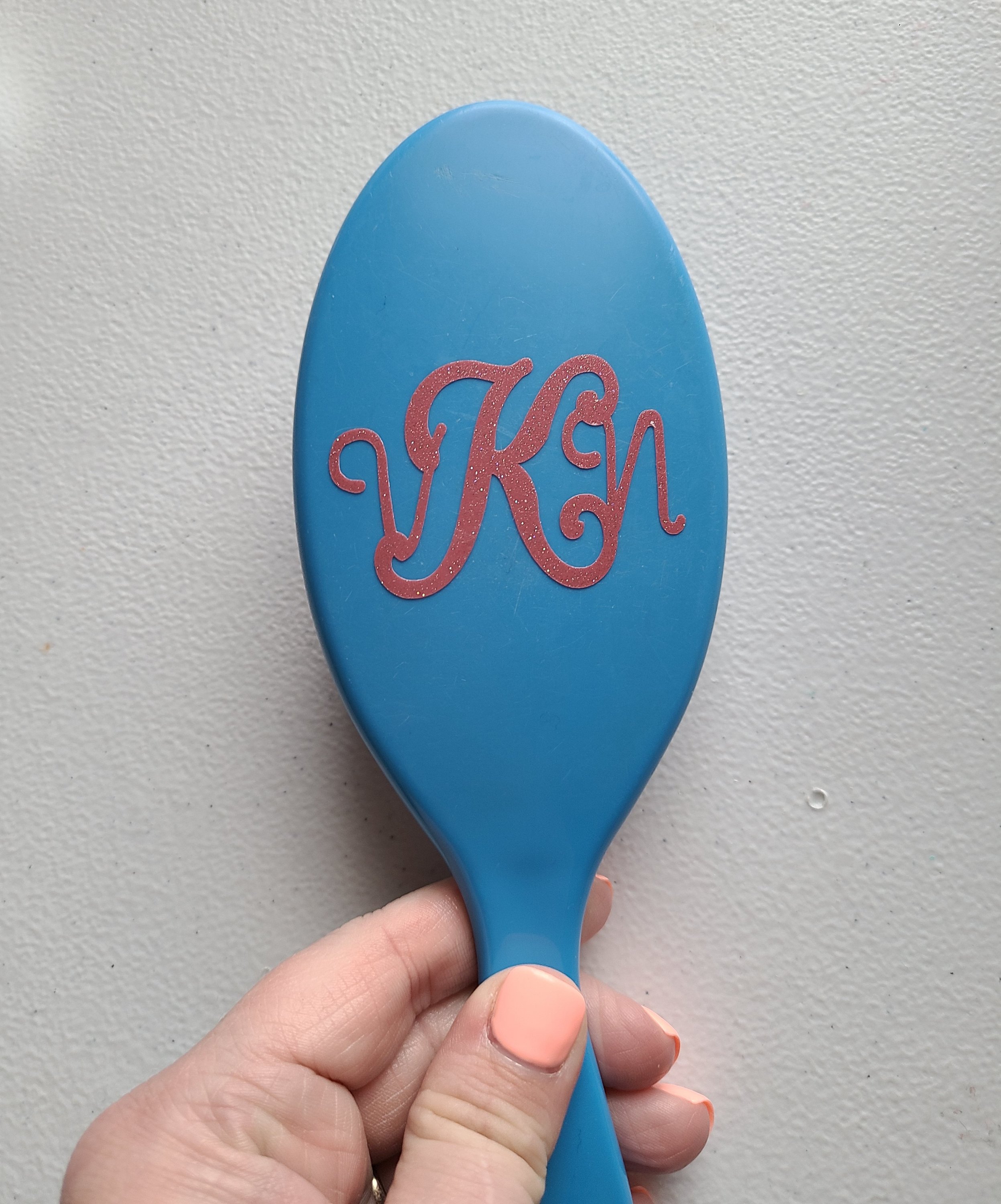 Vinyl monogram applied to a blue hairbrush.