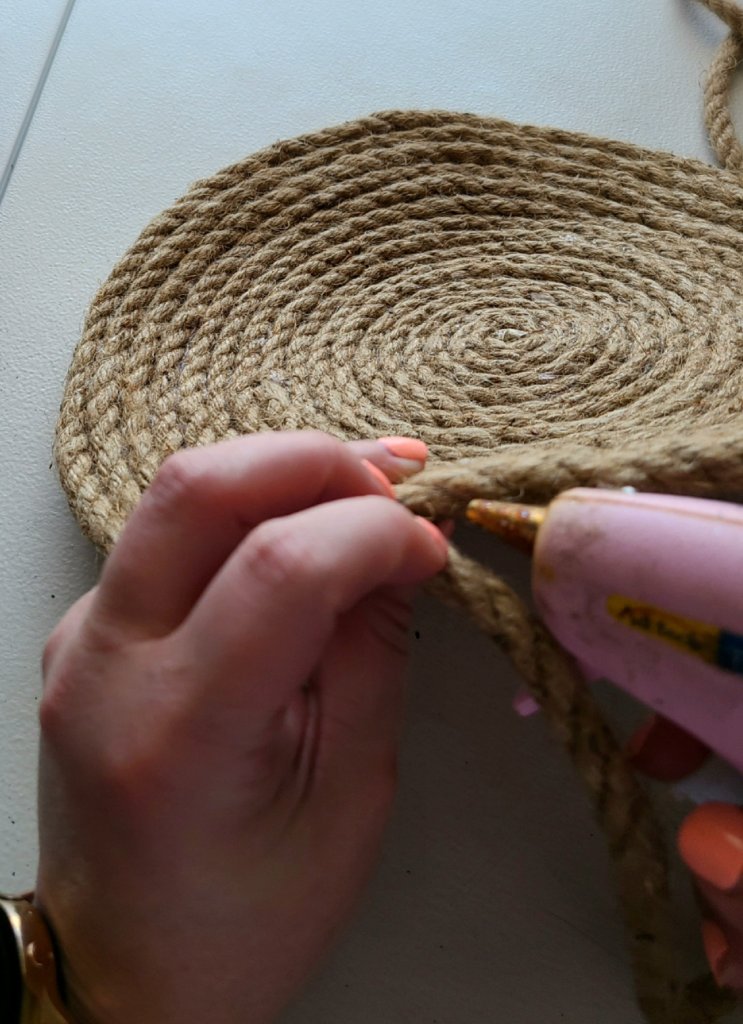 Adding hot glue to the edges of the rope, while rolling it to a flat circle.