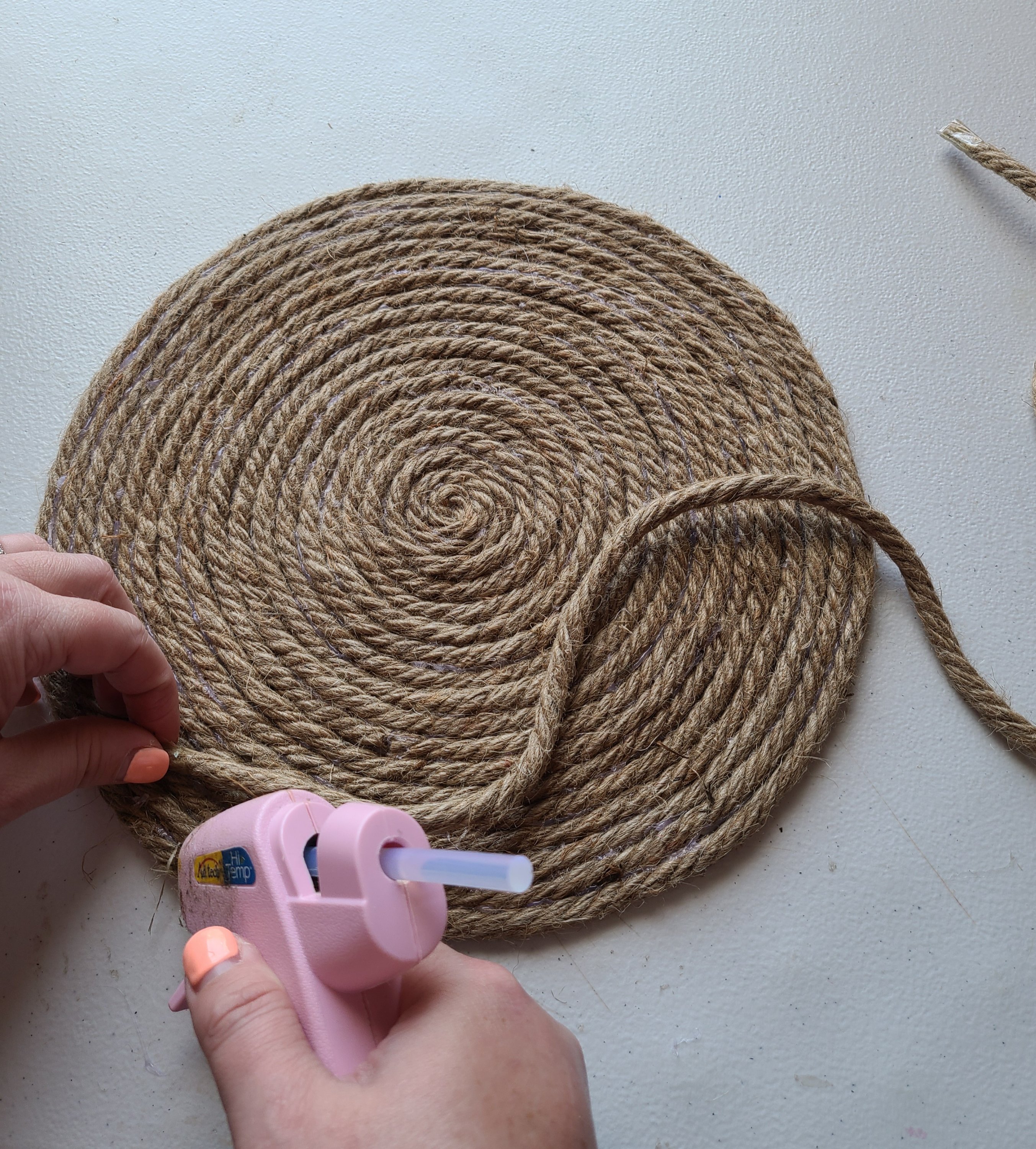 Putting hot glue on the outer ring of the placemat to start building the rope tray.