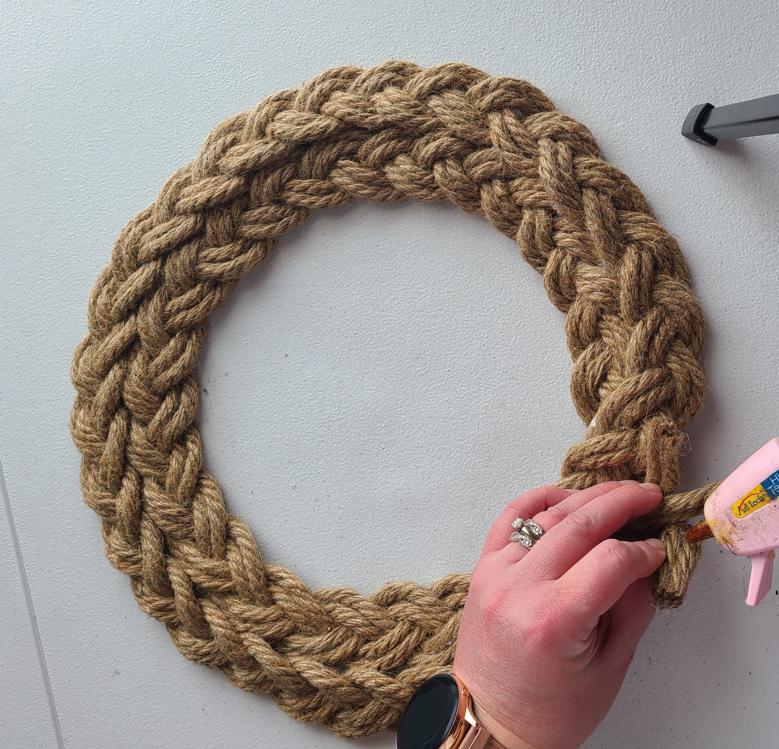 Putting hot glue on the end of the rope to attach it to the wreath.