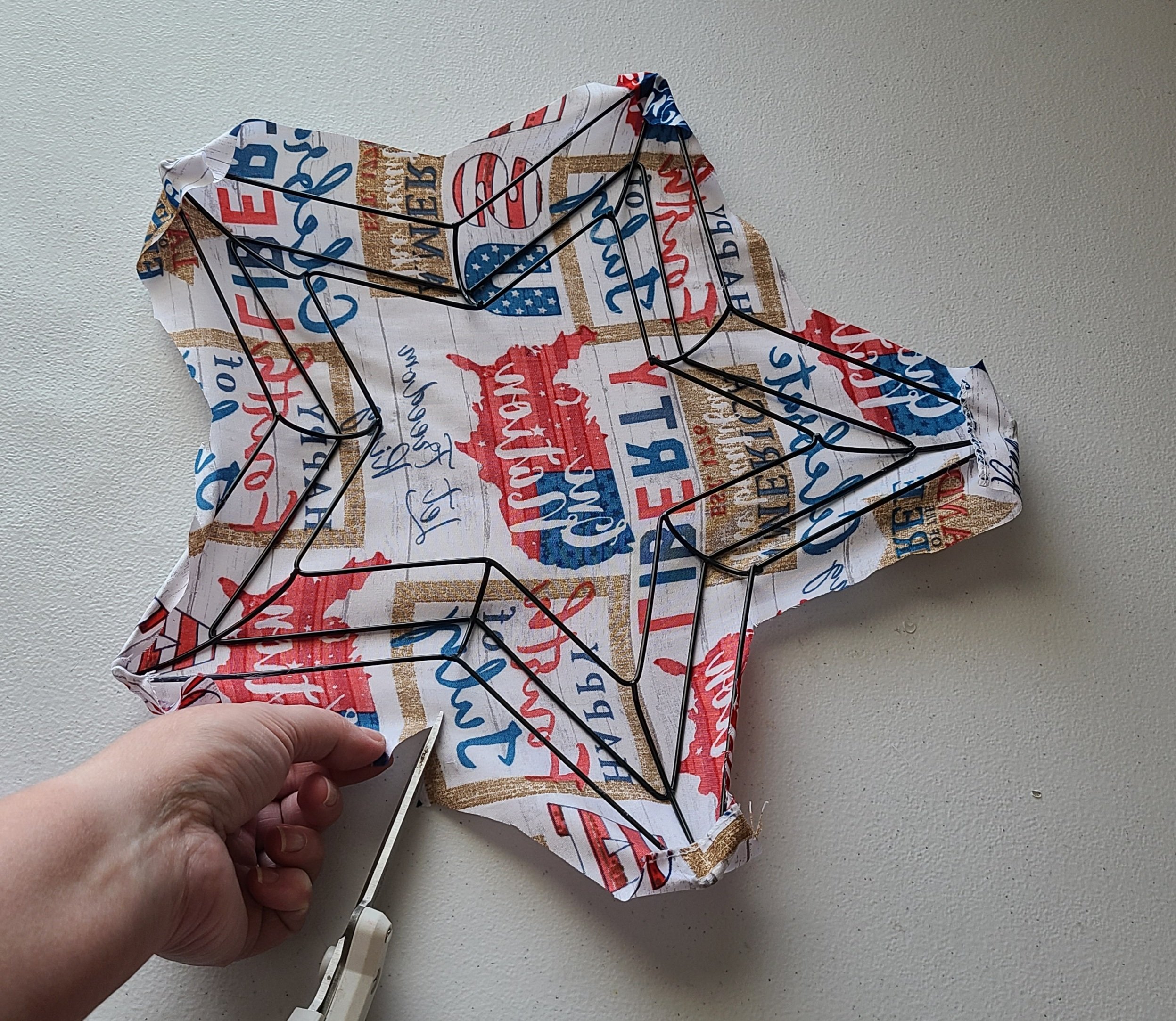 Cutting a line in the patriotic fabric in order to fold it over the back of the star wreath form so it lays flat.