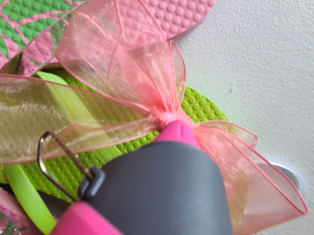 Gluing the bow to the flip flop wreath.
