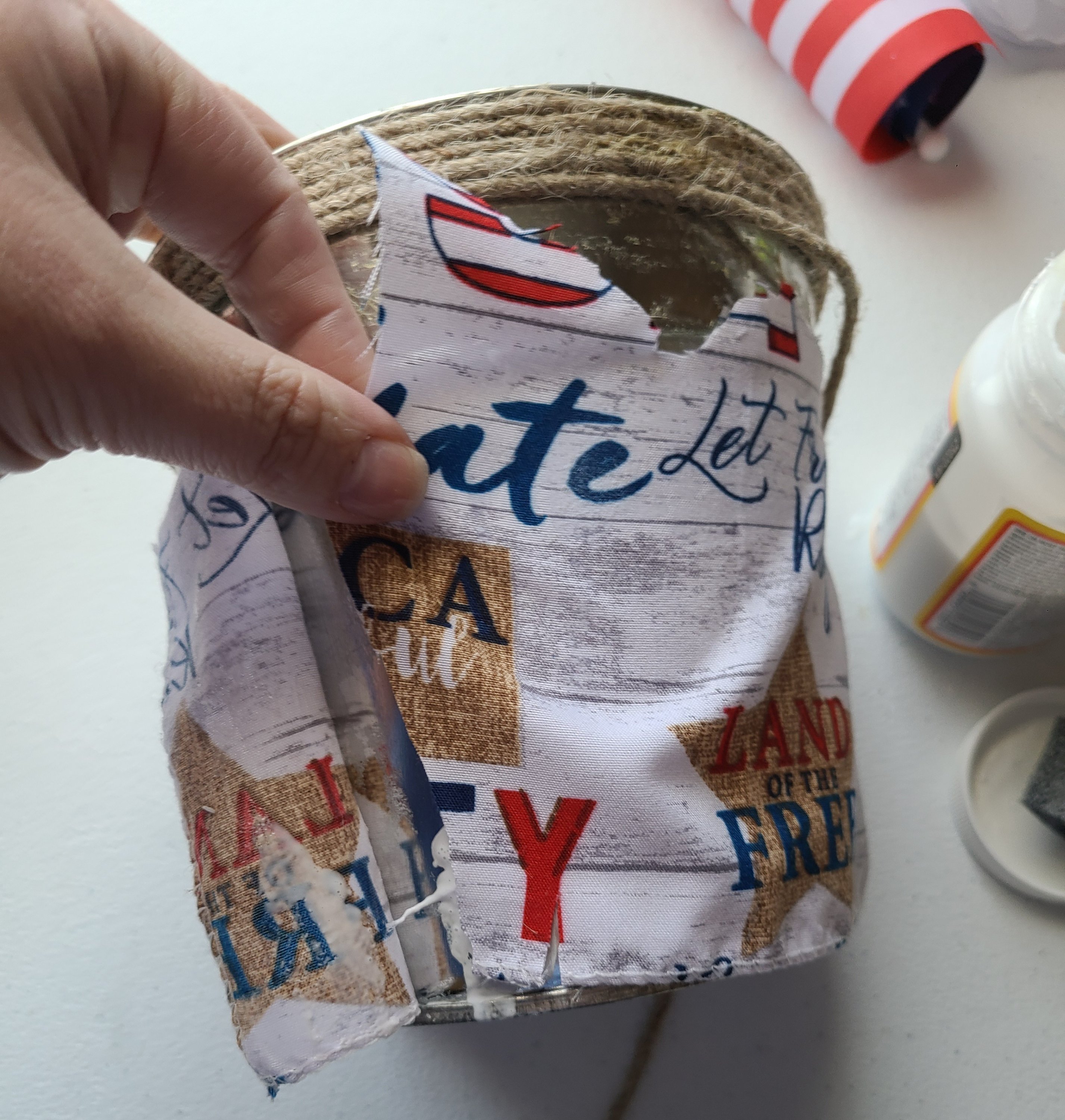 Adding farmhouse style red, white, and blue fabric onto the flowerpot.