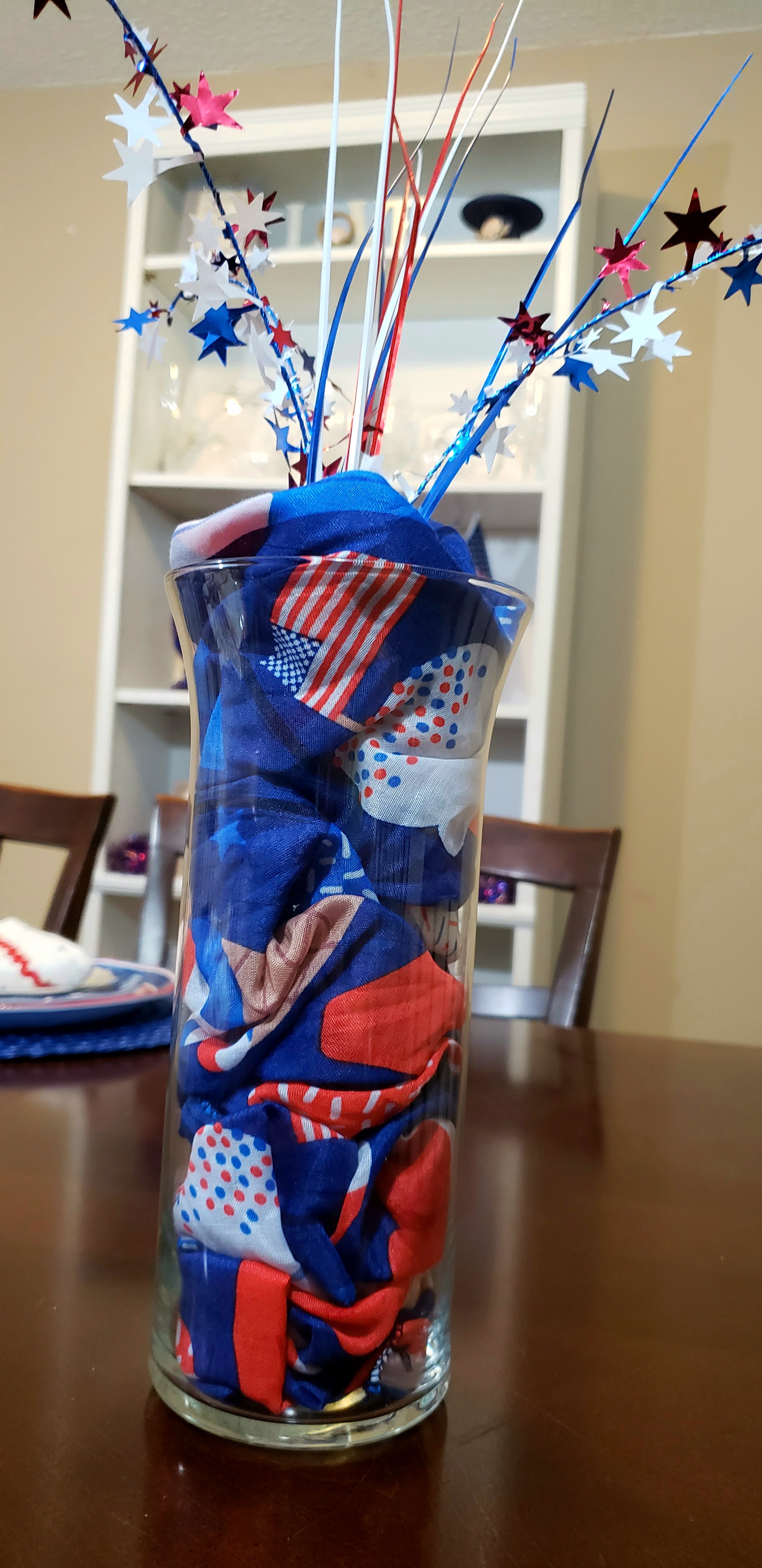 Finished DIY patriotic decorative vase filled with a red, white, and blue scarf and a firework style pick.