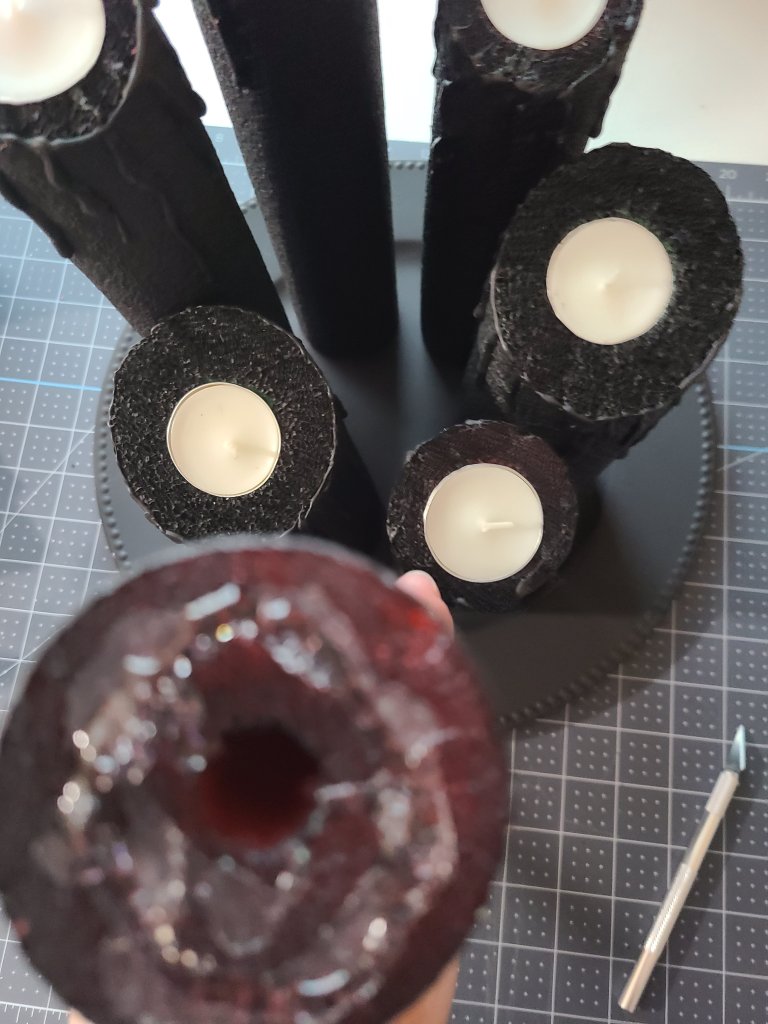 Showing hot glue covering the bottom of one of the pool noodle candles to place on the Halloween candle centerpiece.
