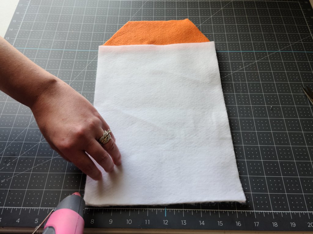 Adding hot glue along the left side of the no sew gift bag.