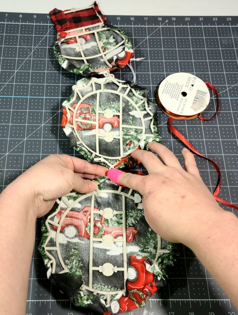 Hot gluing 1/8" ribbon to the back of the connection rings that hold the Dollar Tree snowman together.