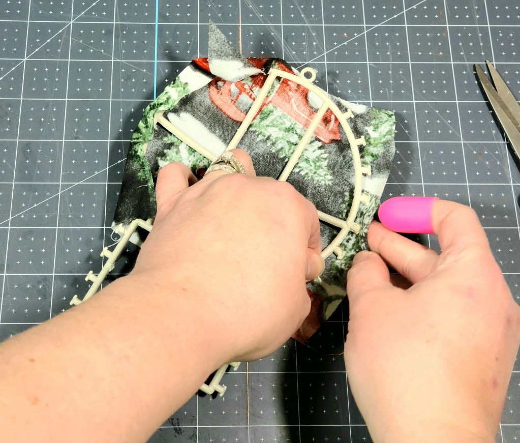 Gluing fabric to the back of the Dollar Tree snowman's head.