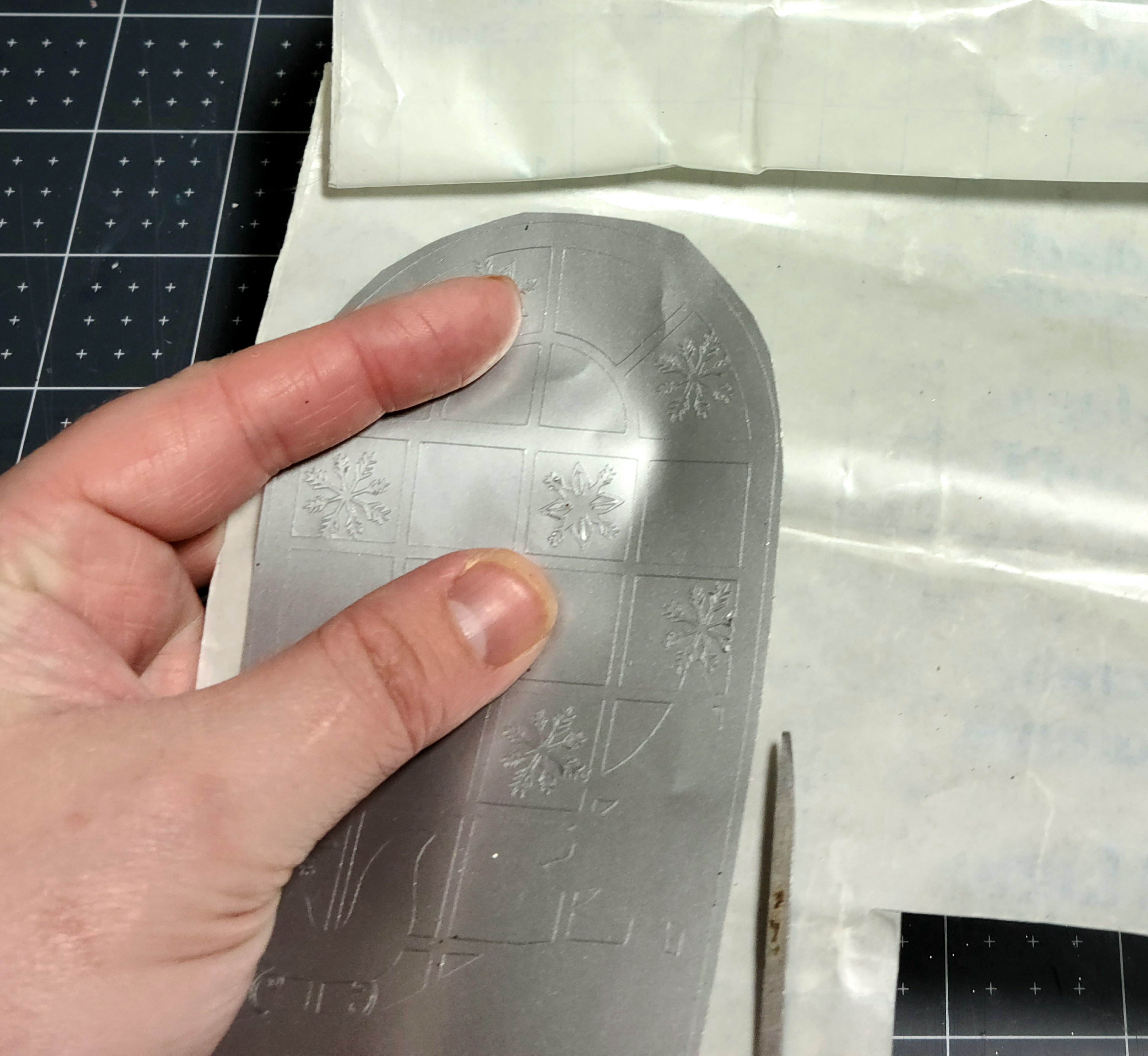 Cutting a piece of contact paper that's just a bit larger than the silver vinyl window-scape design.