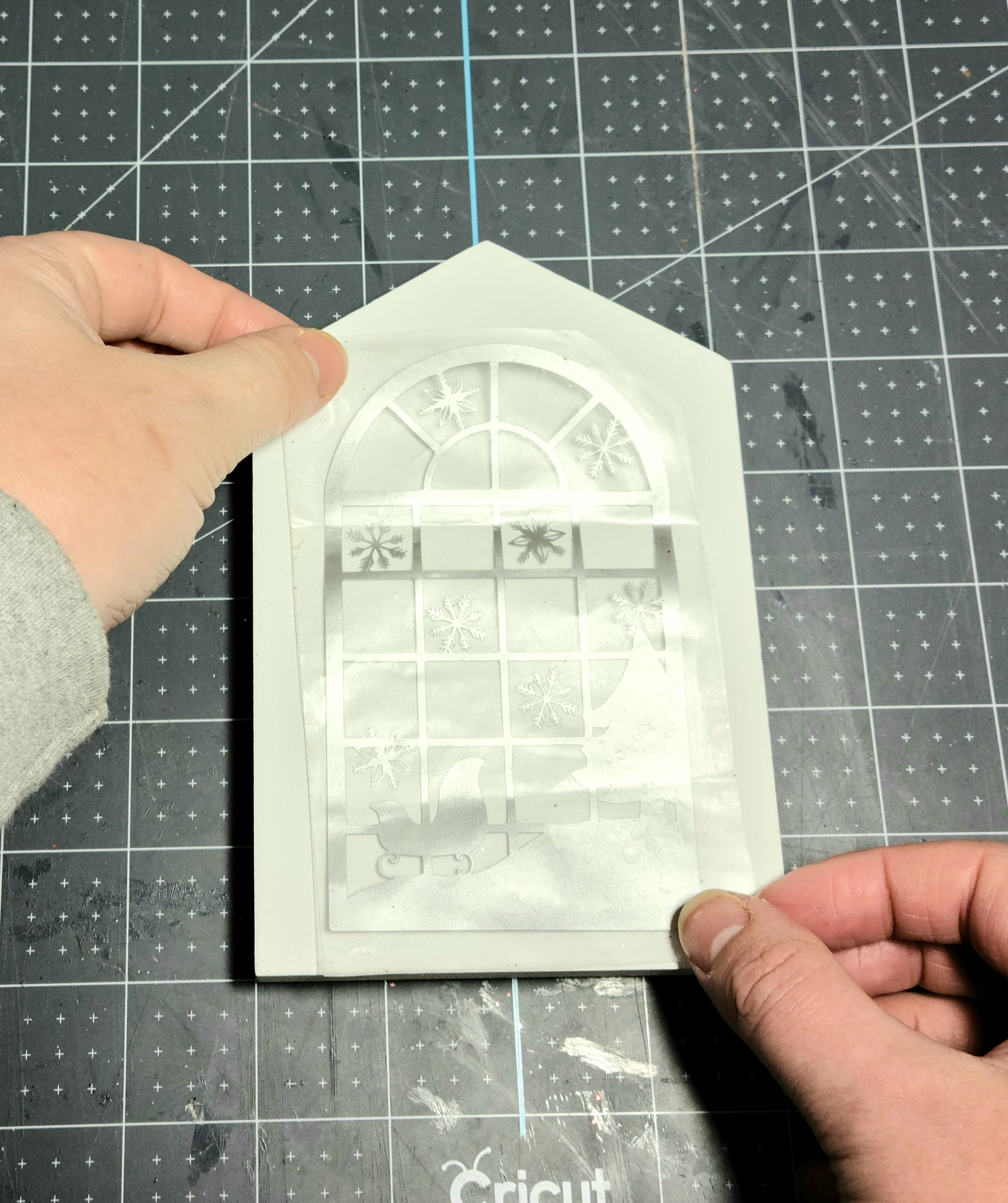 Placing the design on the contact paper on the Dollar Tree Christmas house.