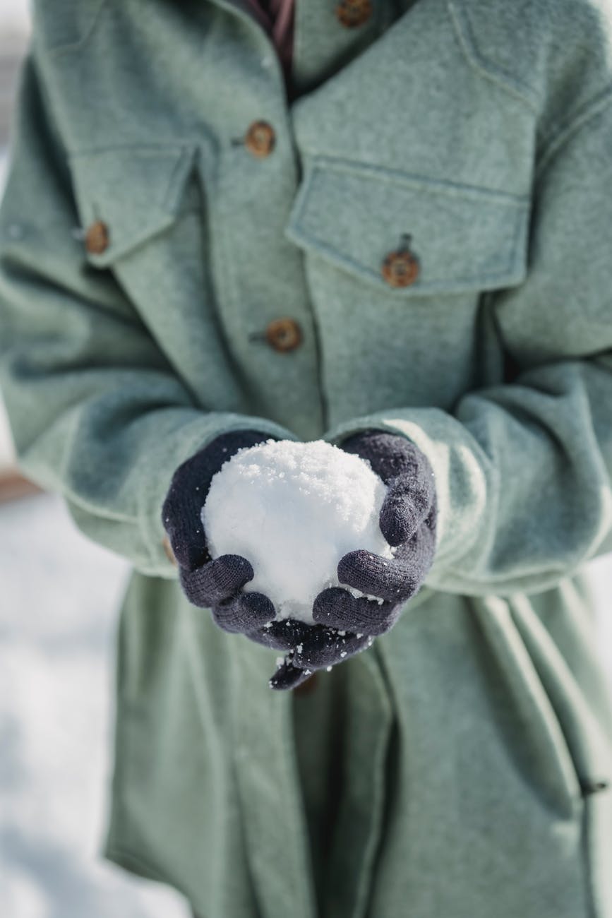 crop faceless woman holding snowball in winter park