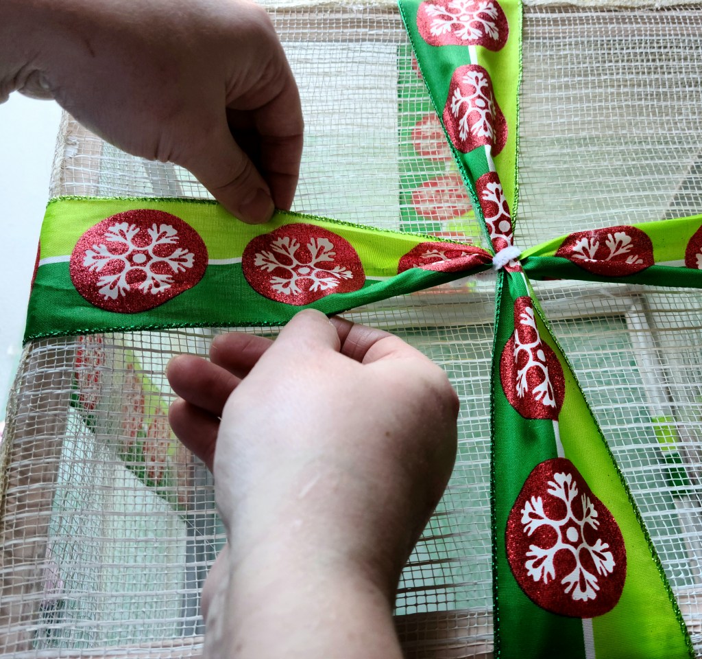 Straightening the ribbons that cross over each other in the middle of the DIY lighted gift box.