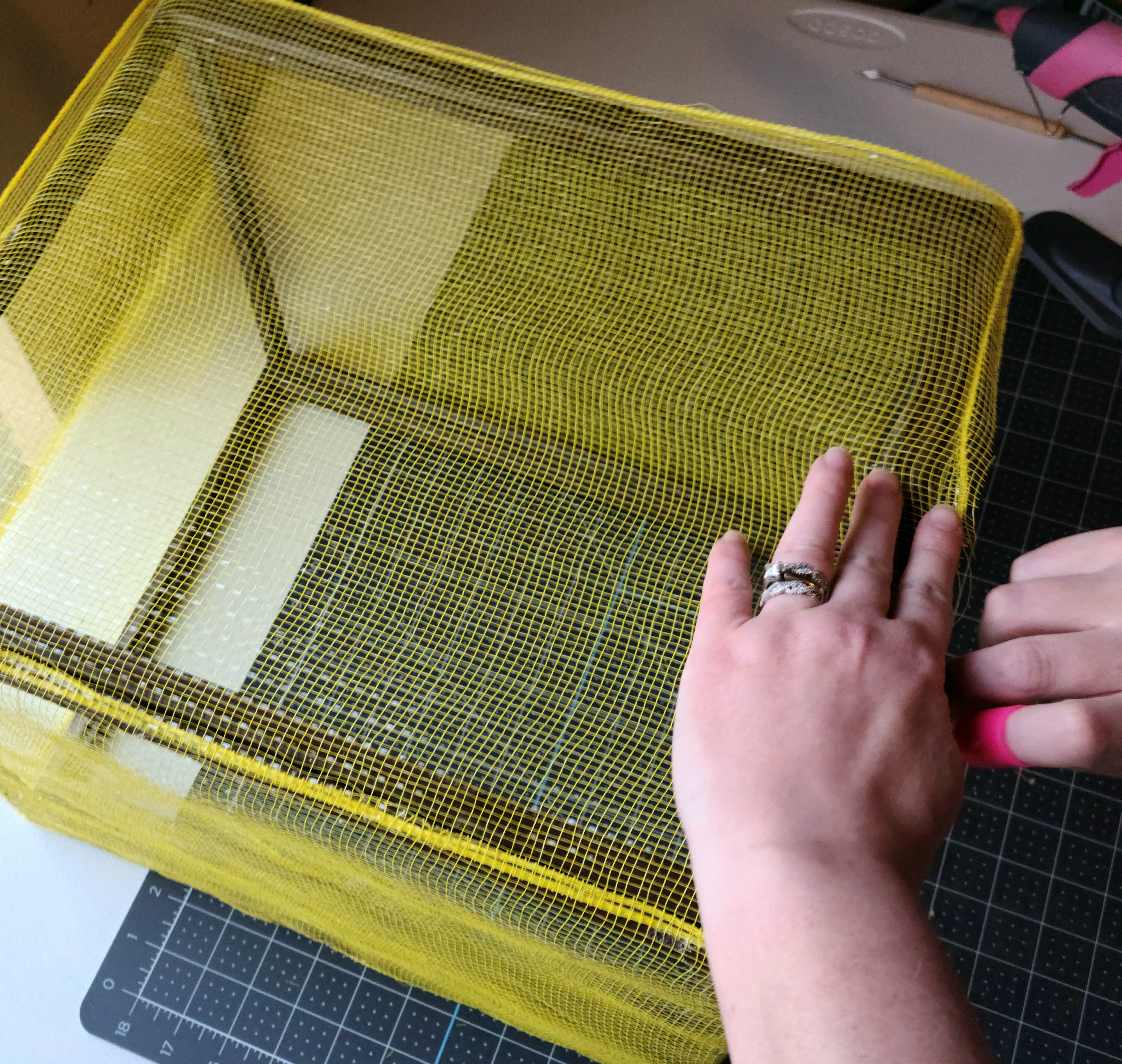 Tucking the deco mesh into the sides of the frame of the DIY lighted gift box.