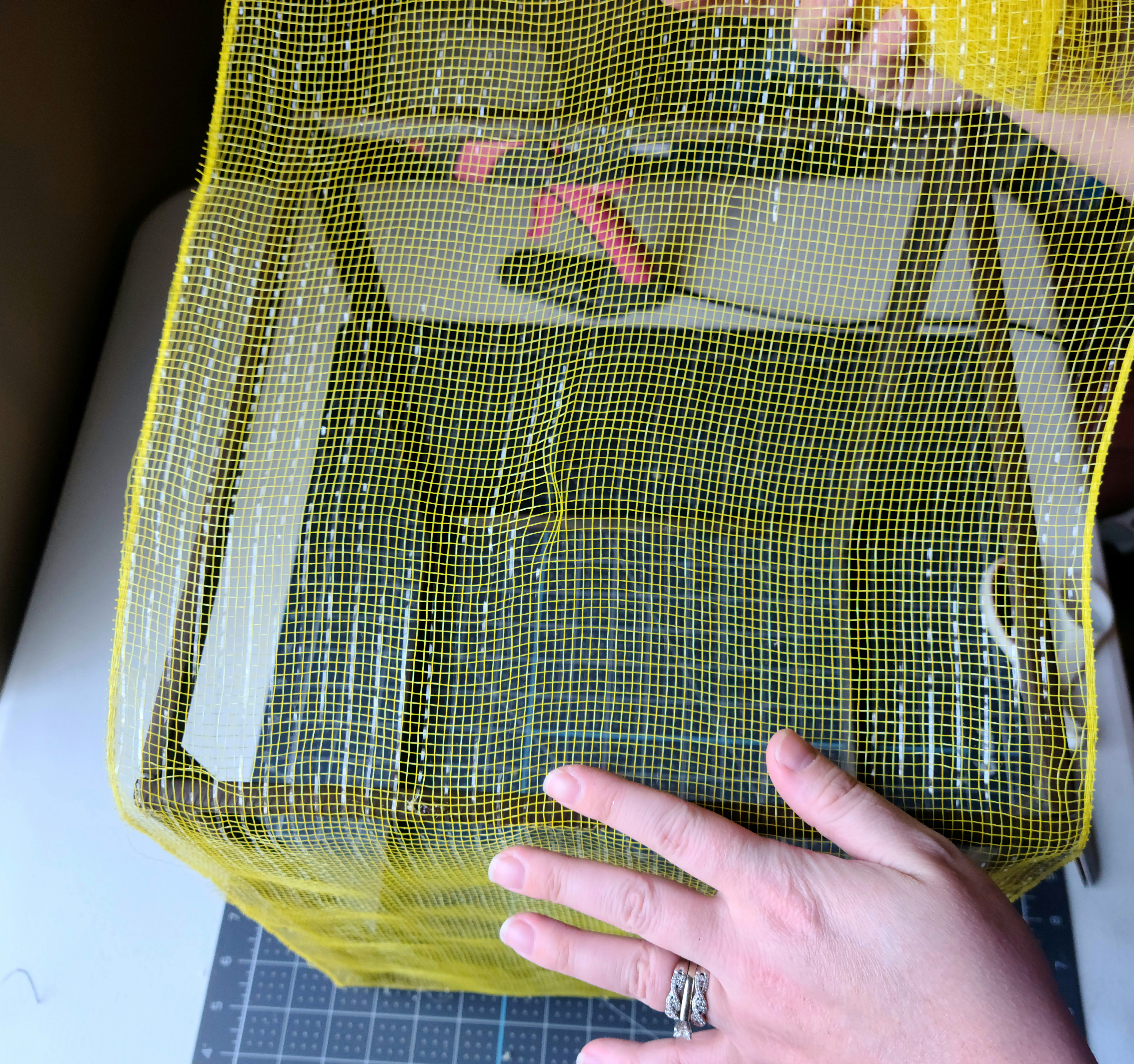 Pulling the deco mesh tight to cover the second side on the frame of the DIY lighted gift box.