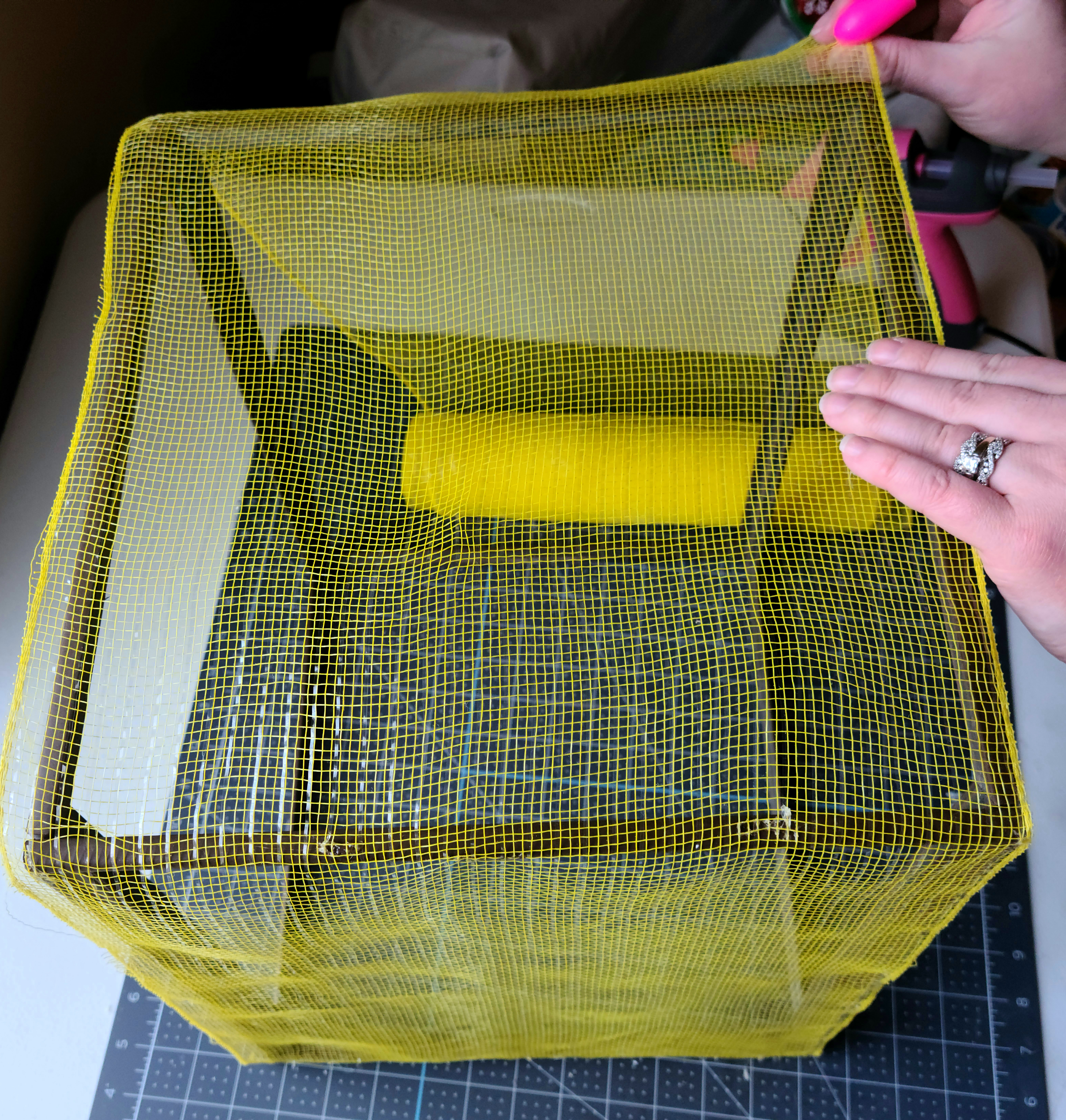 Gluing deco mesh to the second side of the frame of the DIY lighted gift box.