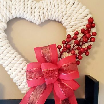 Heart rope wreath with red bow and red berry picks.