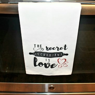 DIY tea towel saying, "The secret ingredient is love," hanging on the stove handle.