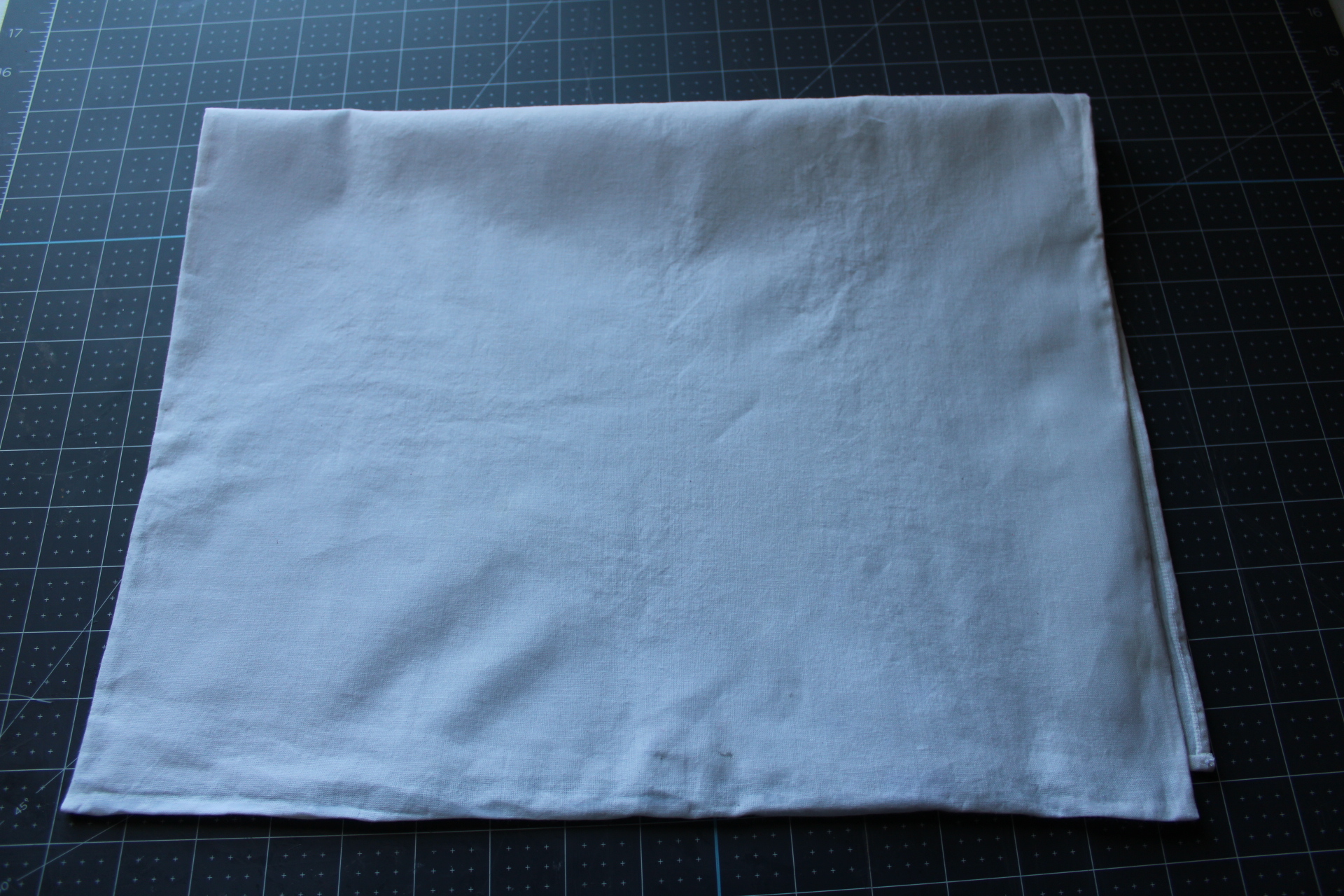 The tea towel folded in half showing the newly no-sew hemmed edges.