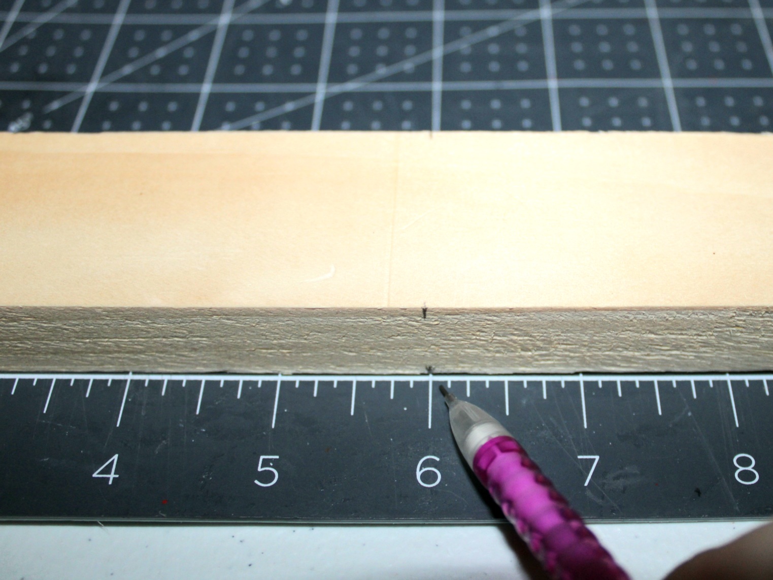 Marking a 12" piece of wood at the 6" mark to cut it to be a step on the DIY tea towel ladder.