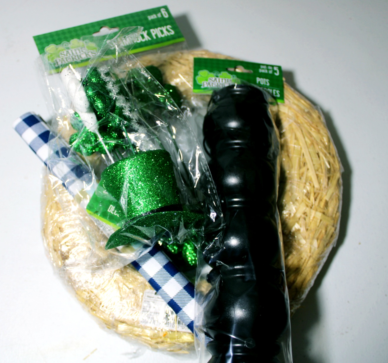 St. Patrick's Day wreath supplies: buffalo check fabric, straw wreath form, shamrock picks, and hat pick.