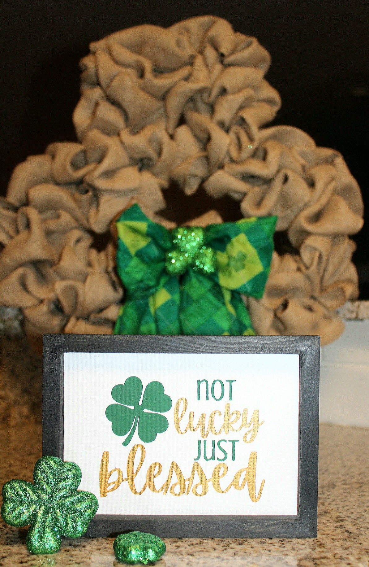 "Not lucky just blessed" Cricut stencil sign in front of a burlap shamrock wreath.