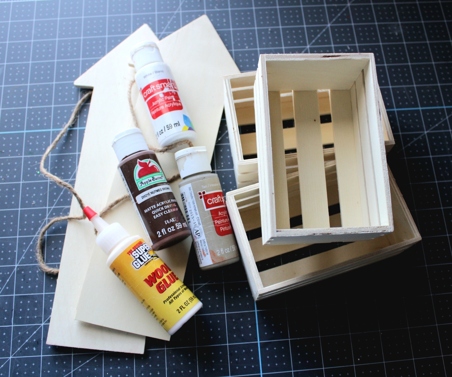Supplies for a Dollar Tree crate shelf: 2 wood arrows, 3 small crates, wood glue, and black, tan, brown, and white acrylic paints.