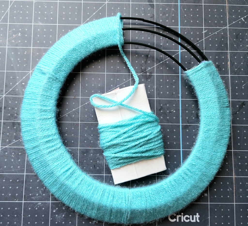 Wrapping the spring wreath in turquoise yarn.