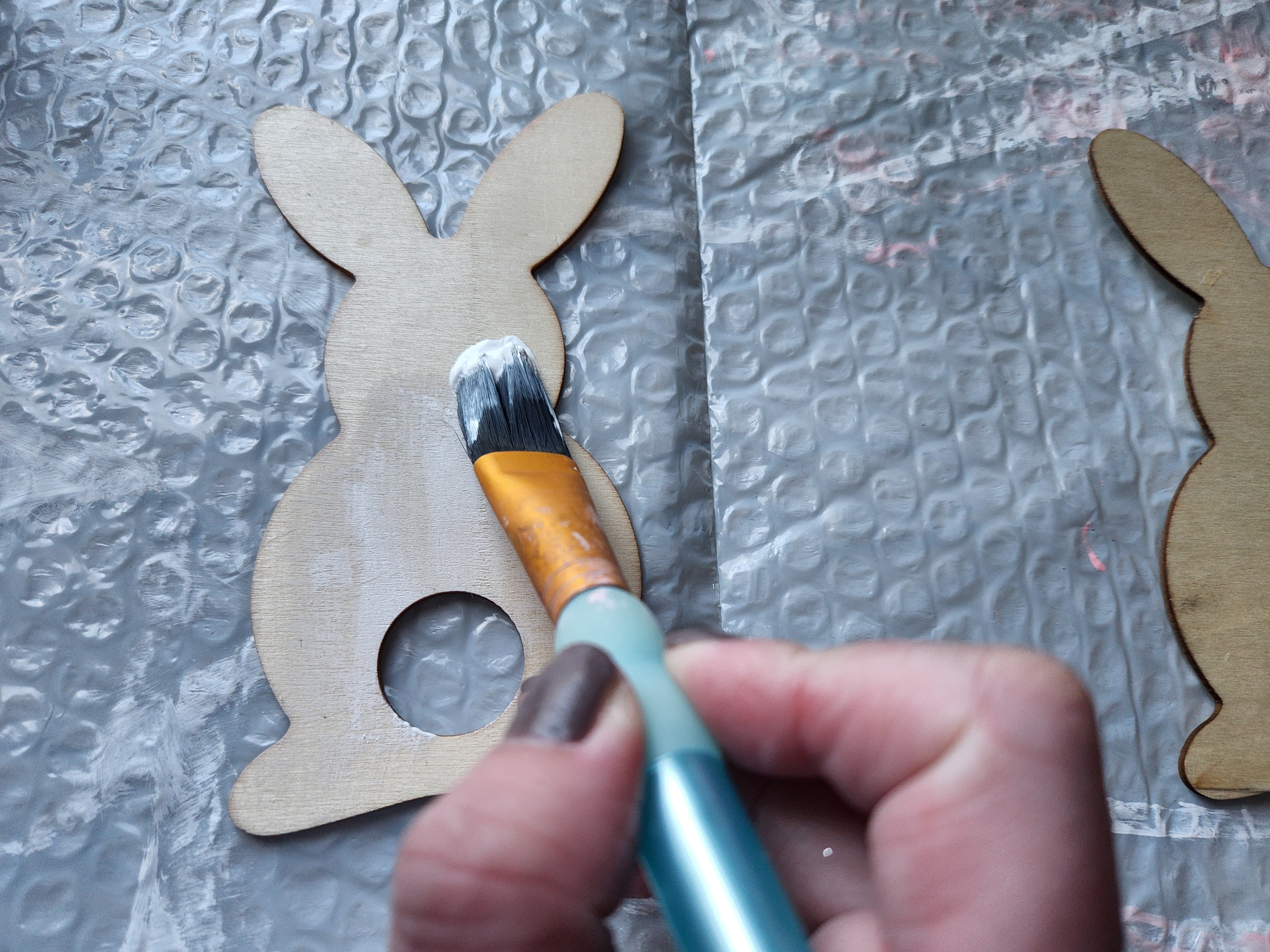 Painting the wood bunny white to paint a buffalo check pattern to place on the spring wreath.
