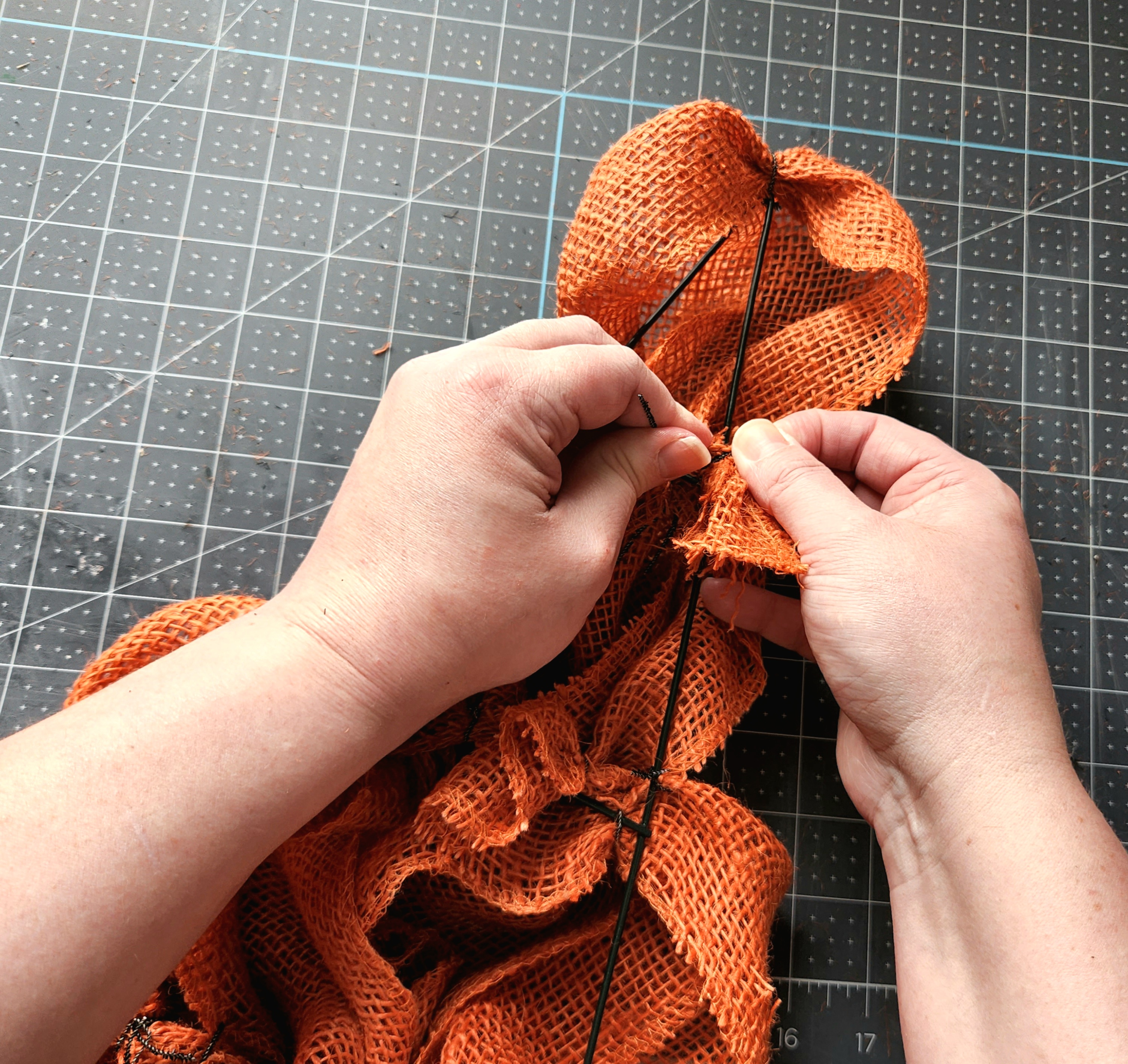 Attaching the orange burlap to the last wire in the middle of the carrot wreath form.