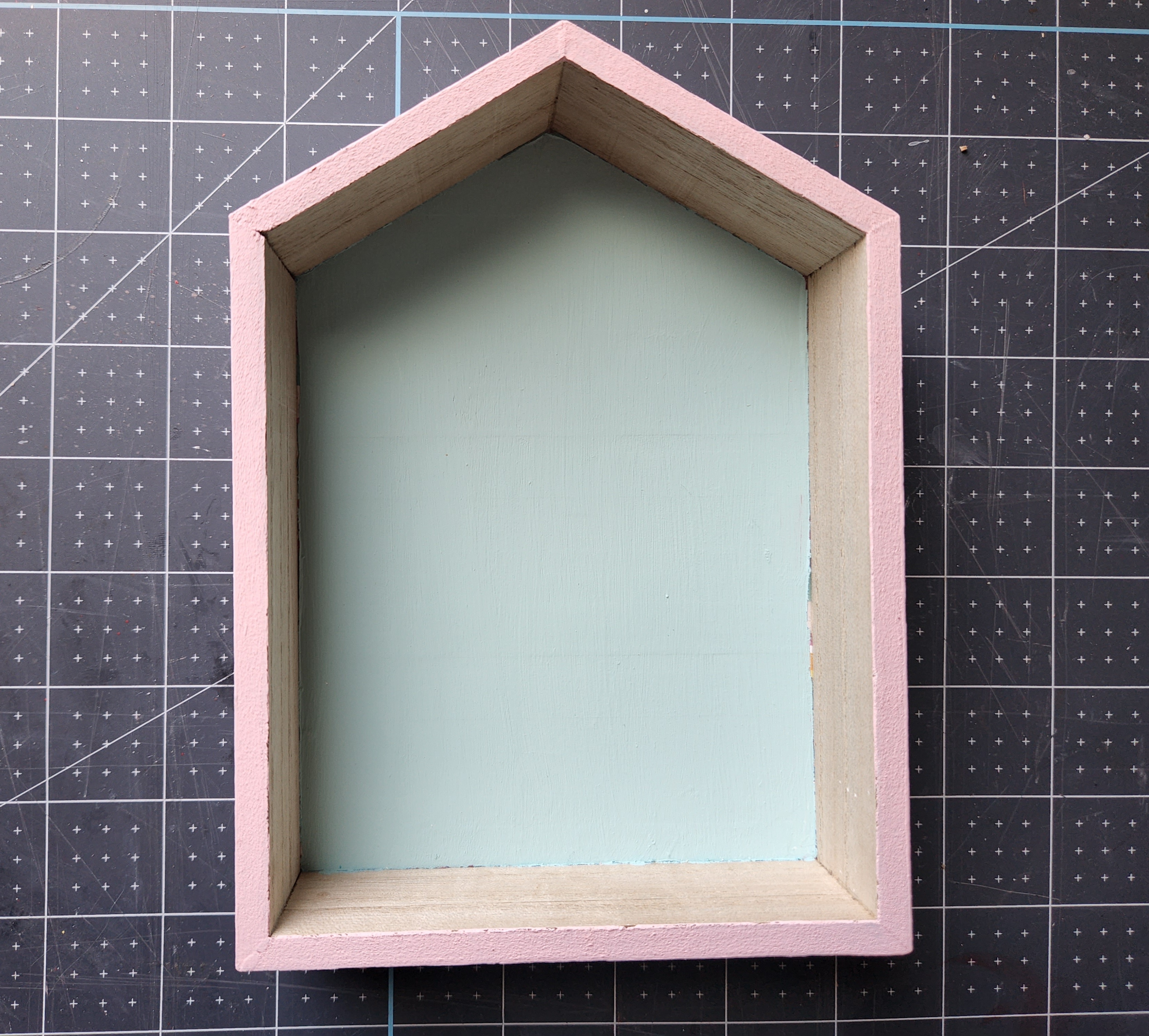 Spring Dollar Tree house with the outside painted with pink chalk paint and the inside panel painted robin's egg blue.