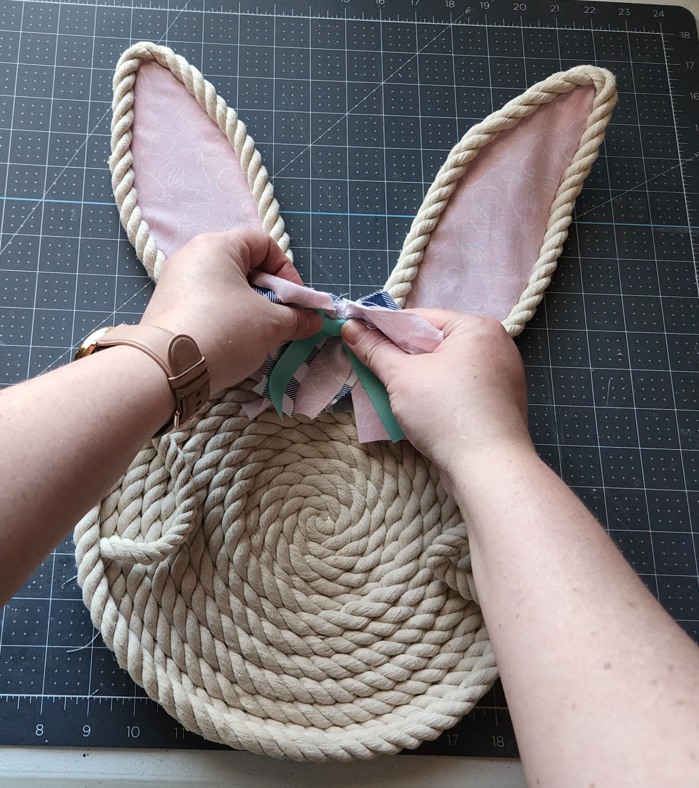 Placing a bow onto the glue at the top of the rope bunny tray.