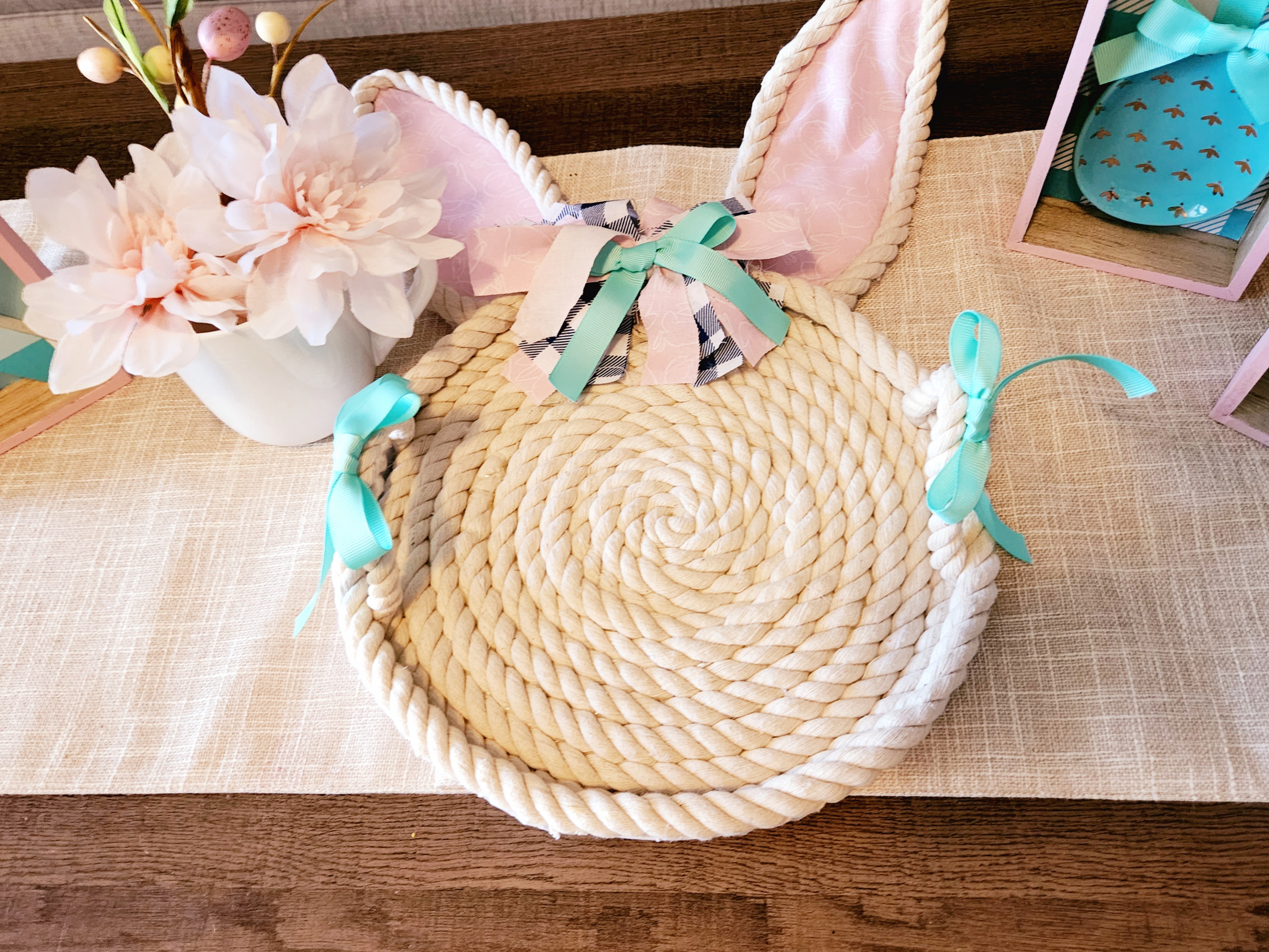 Spring decor rope bunny tray complete with a white mug, flowers, and Easter egg pick on it.