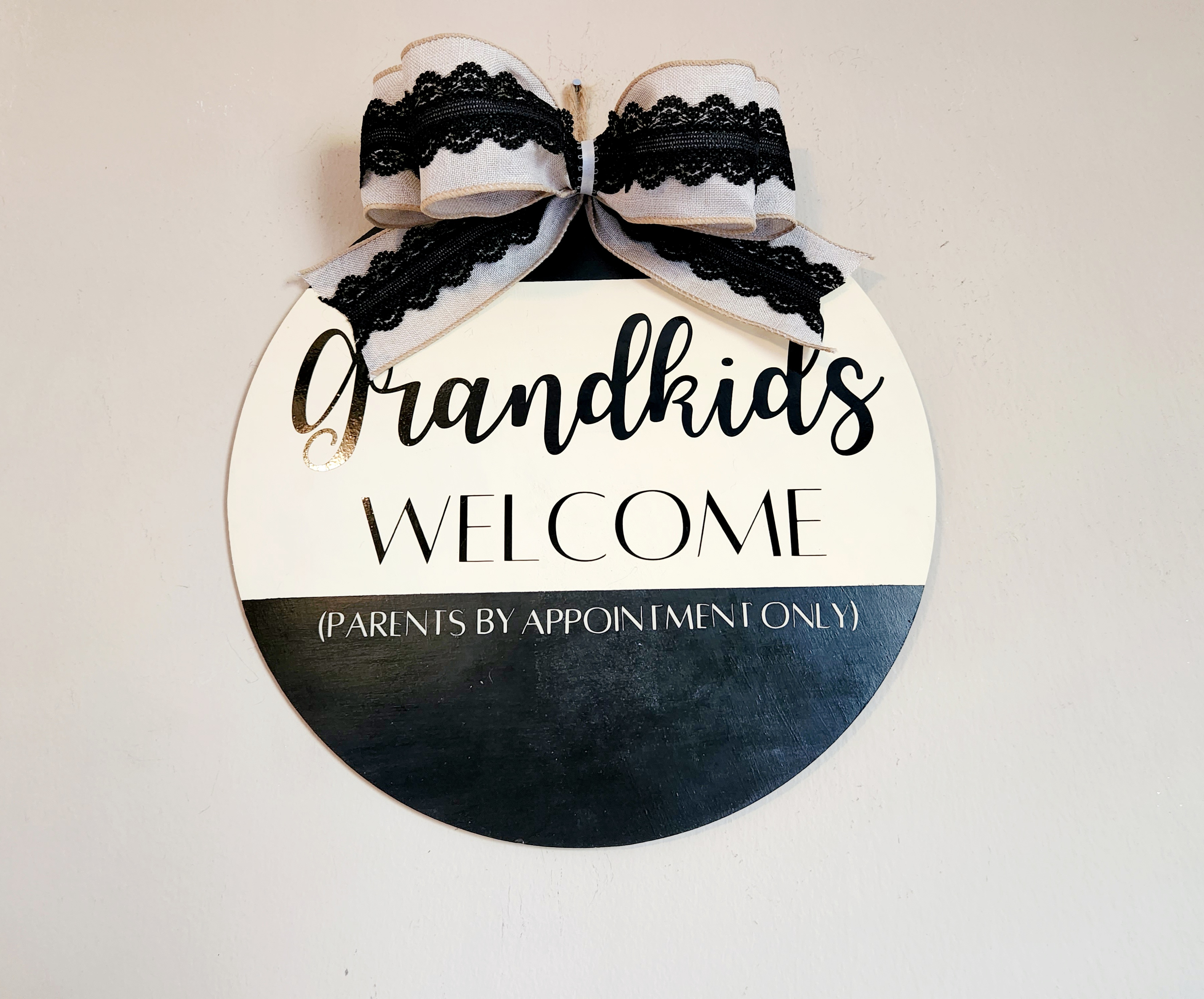 Khaki linen and black lace bow at the top of the Mother's Day gift round sign saying, "Grandkids welcome (parents by appointment only)"