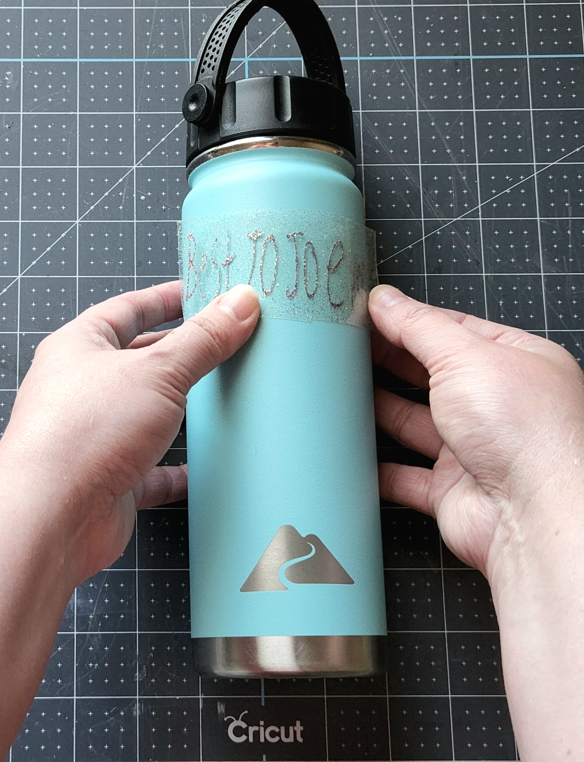 Placing a childs handwriting on the tumbler after cutting it with a Cricut.