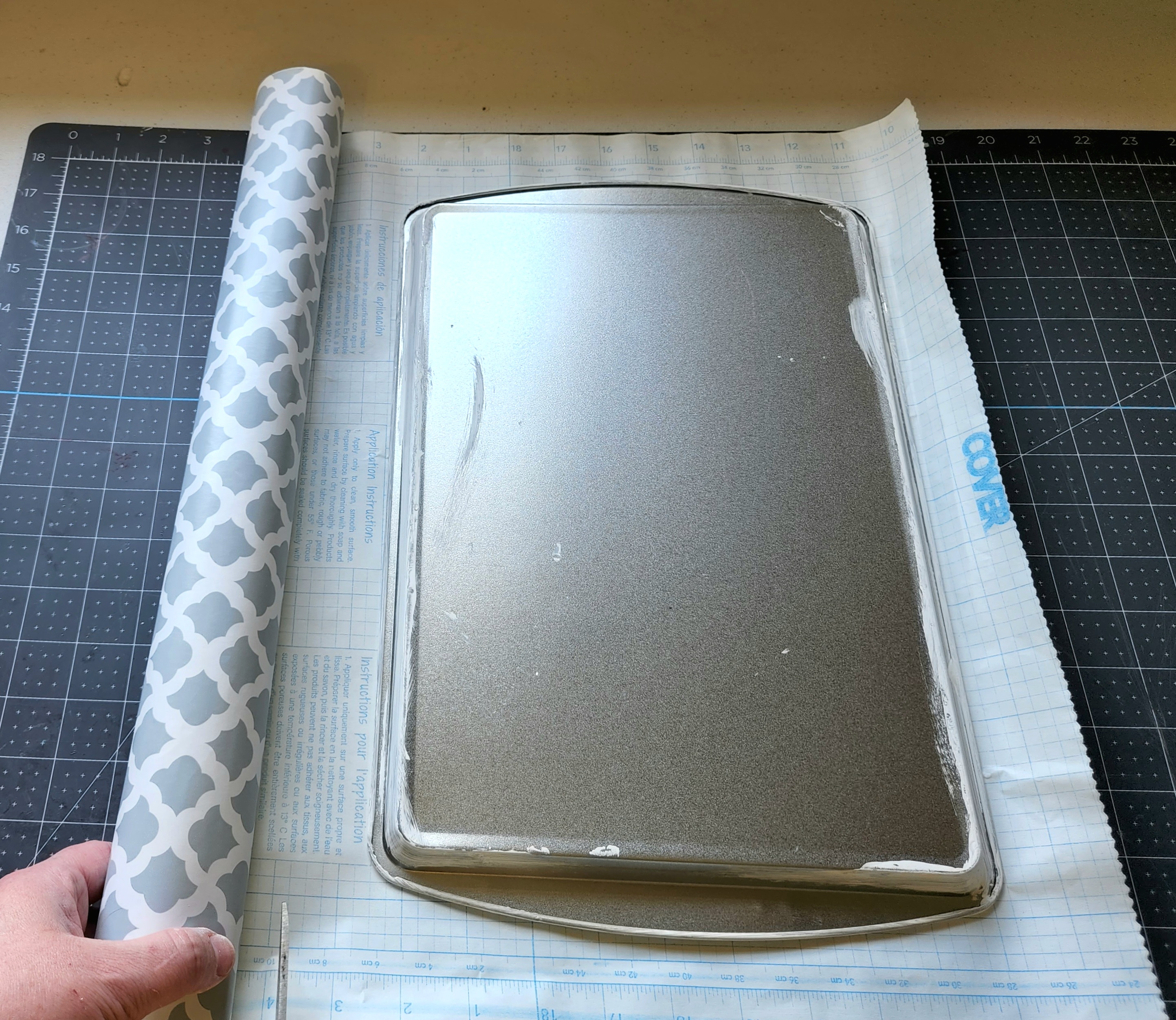 Cutting contact paper to cover the baking sheet.