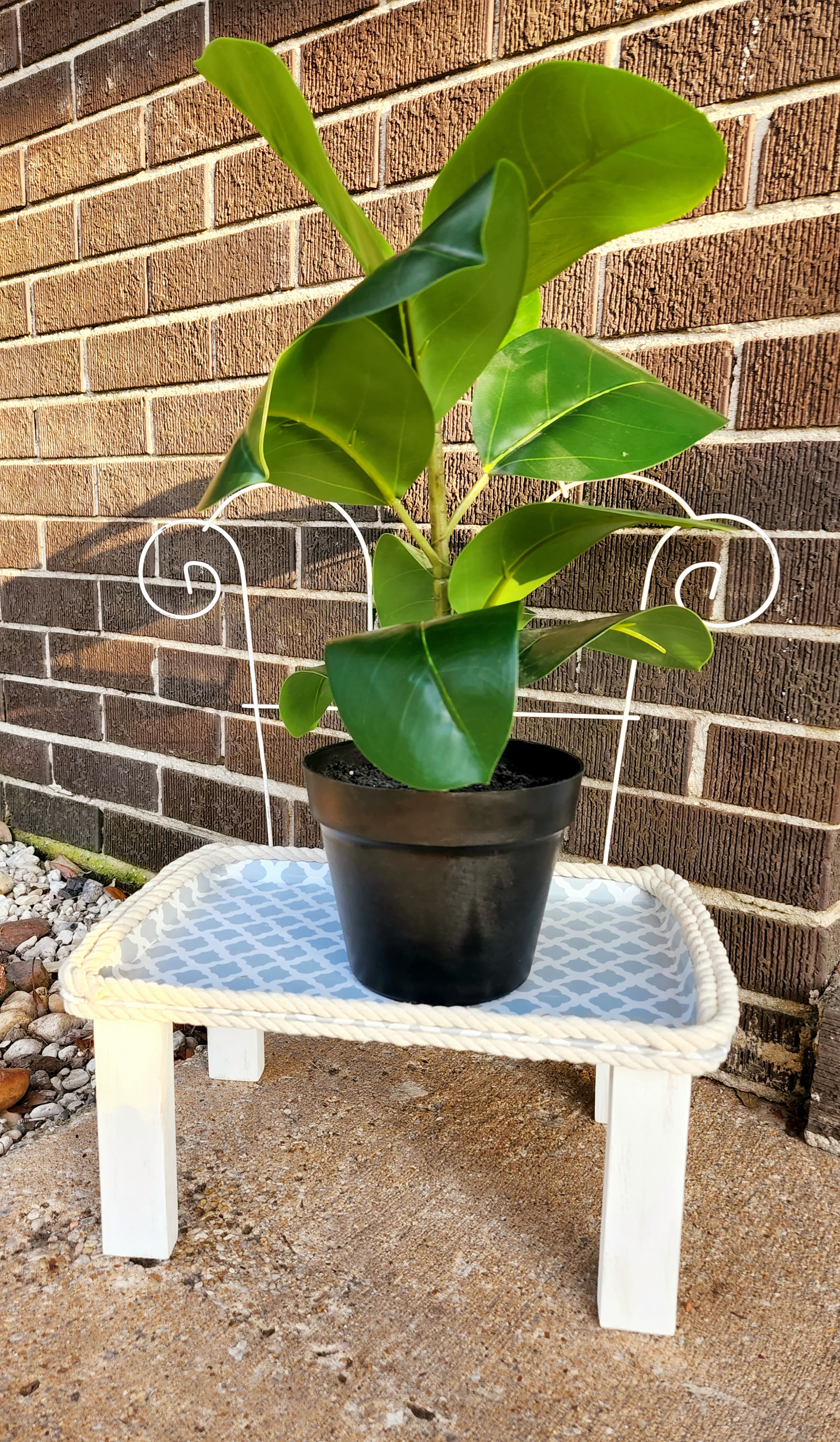 Outdoor plant stand on my porch with a plant placed on it.
