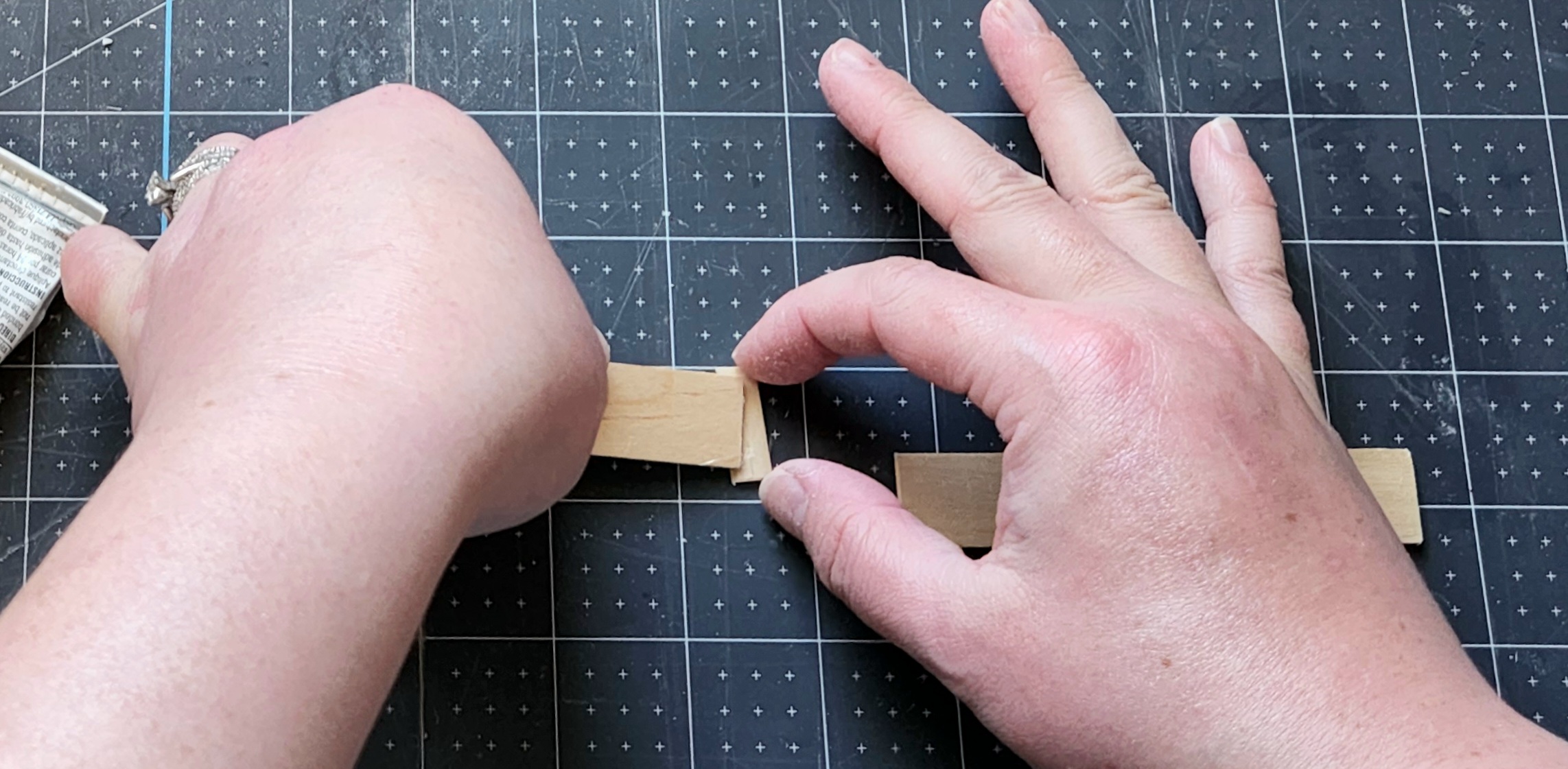 Placing a 4" craft stick onto the middle of a 1" stick.