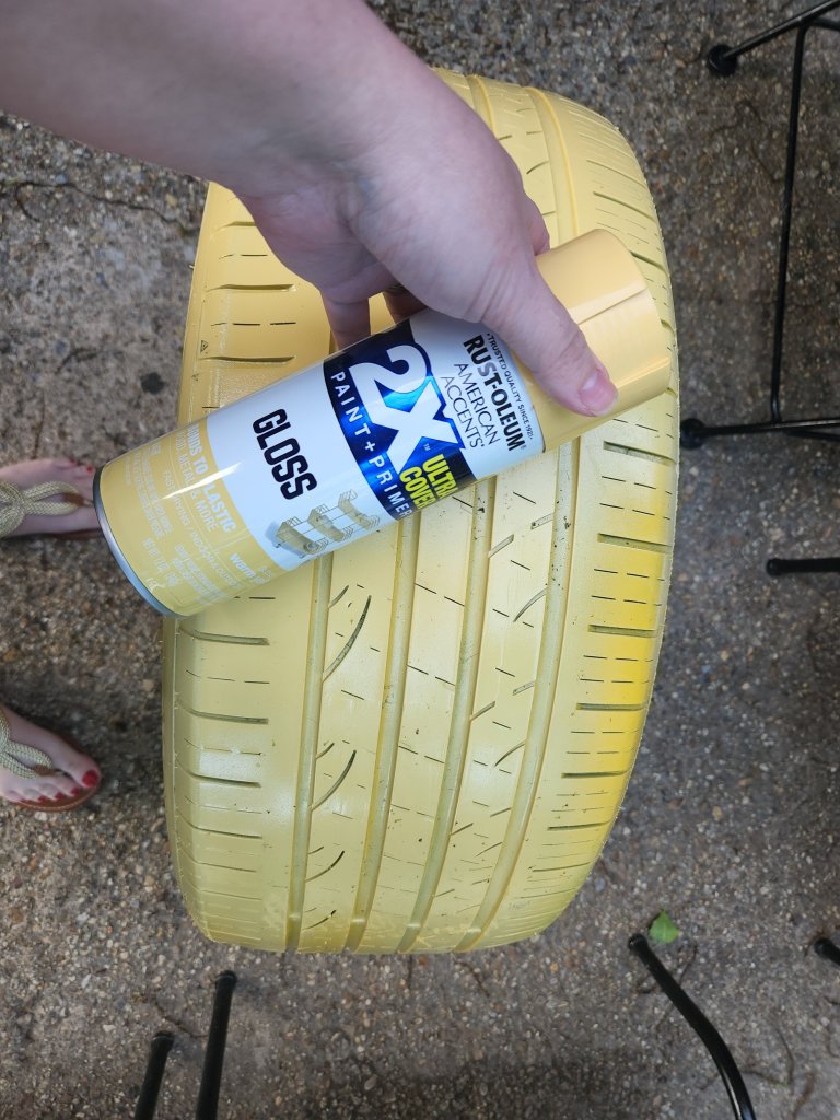 Rustoleum warm yellow paint and primer with a large tire spray painted with it.