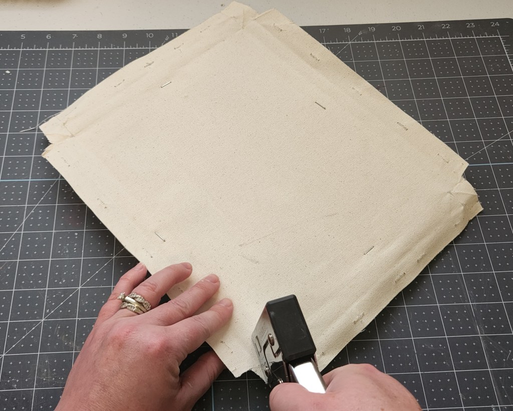 Stapling the canvas back on the wood frame.