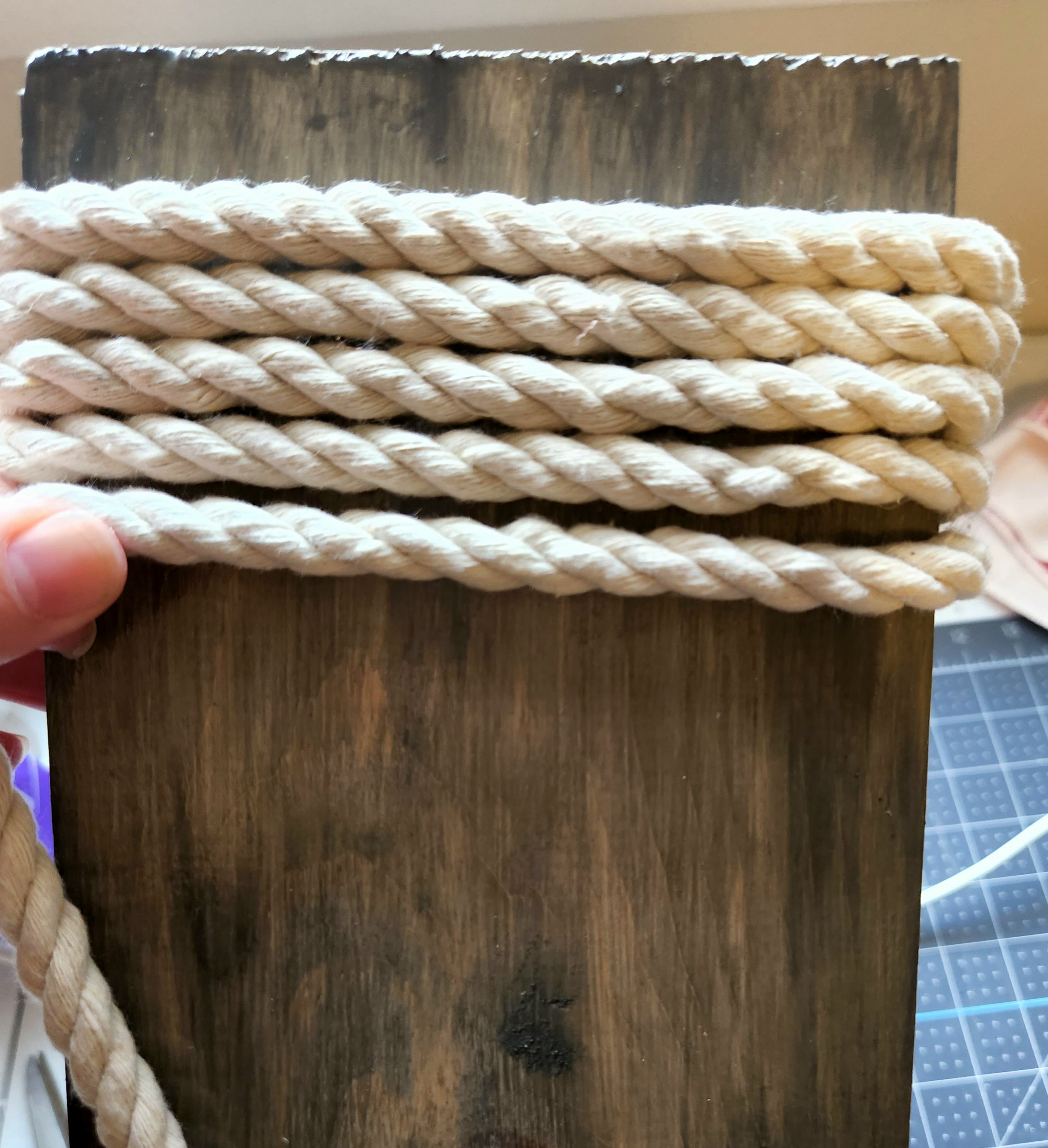 Adding hot glue to the end of the cotton rope to hold on the DIY porch sign.