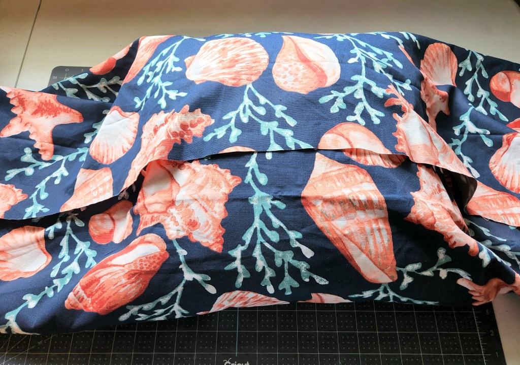 Bringing the bottom of fabric up to cover the bottom half of the pillow.