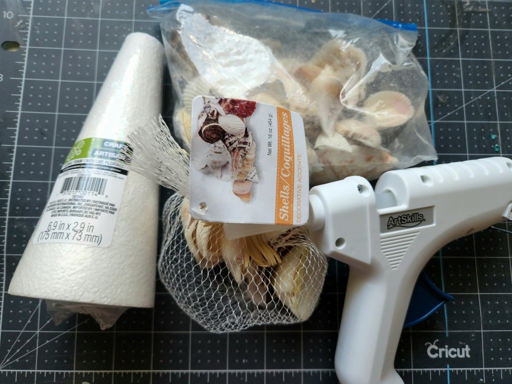 Seashell Christmas tree supplies: hot glue gun, styrofoam cone, and seashells.