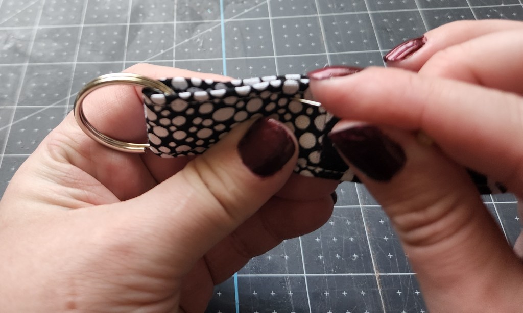 Folding the key fob so that the two ends of the shorter section of fabric line up.