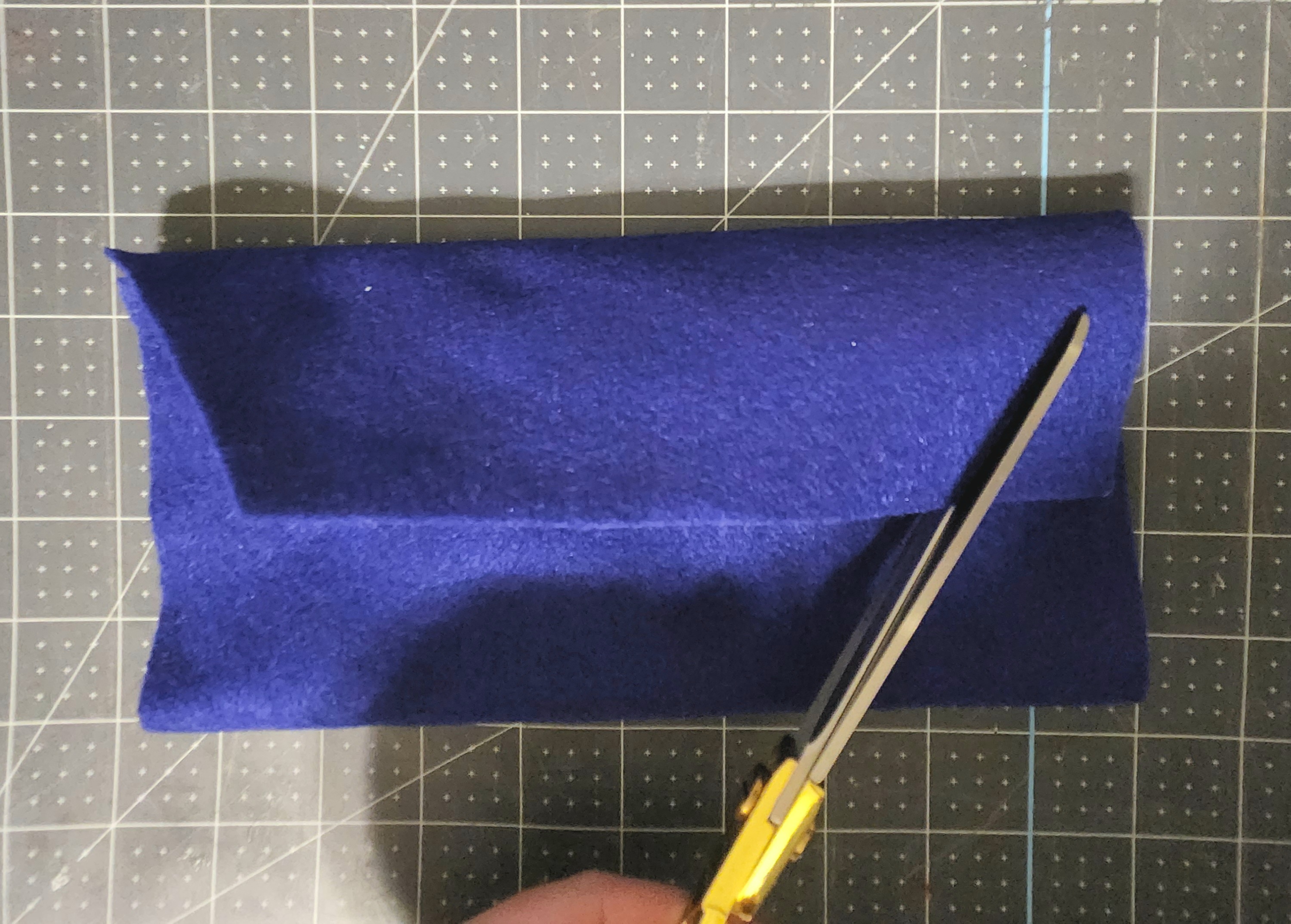 Cutting the top flap of felt into an envelope shape, diagonally from the bottom to the corner.
