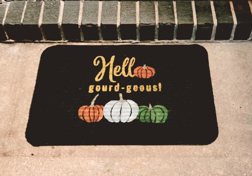 Fall doormat with pumpkins and "hello gord-geous" painted on it.