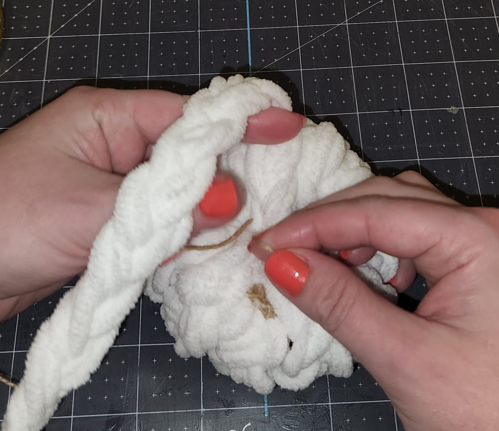 Tying off the end of the braided yarn with a piece of twine before cutting it off from the pumpkin.